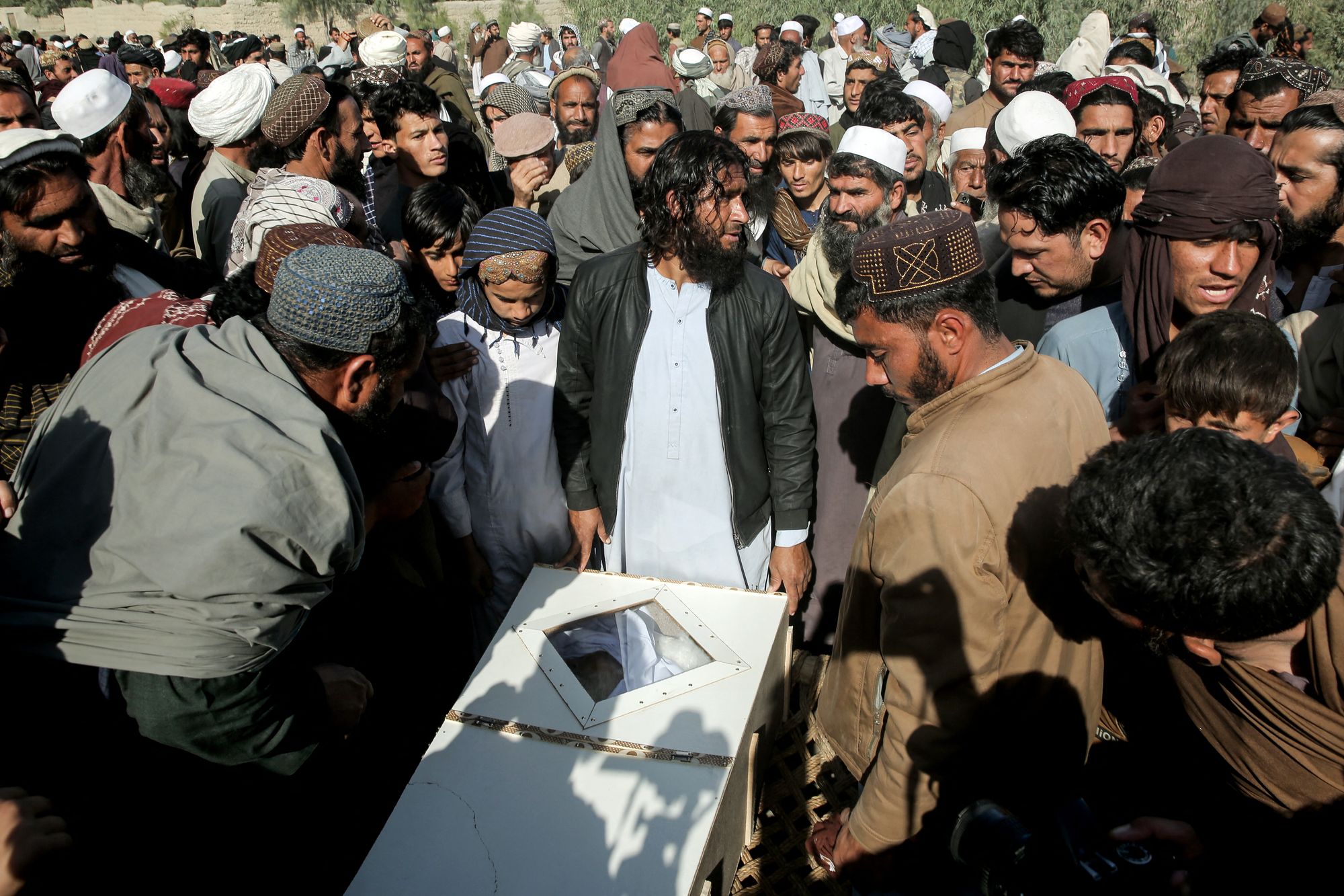 Afghan relatives and mourners surround the body of a victim, killed in an overnight Pakistani air strike, during a mass burial ceremony at the Girdi Kas village in Bihsud district, Nangarhar province