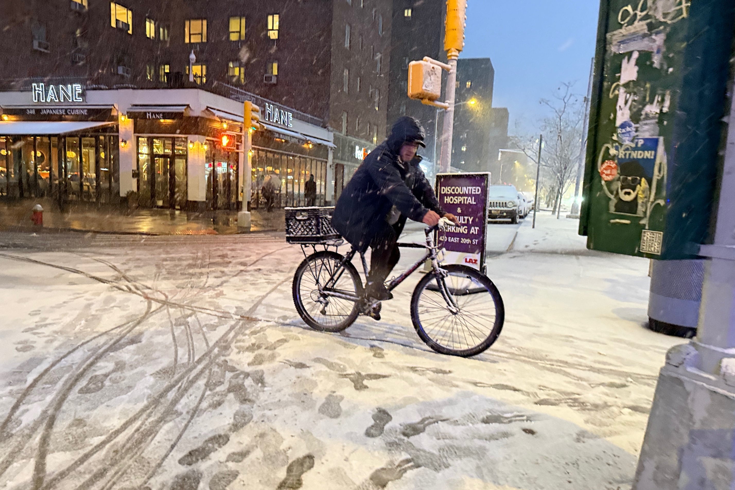 A man rides a bicycle at the beginning of an intense snowstorm on 20th Street and First Avenue