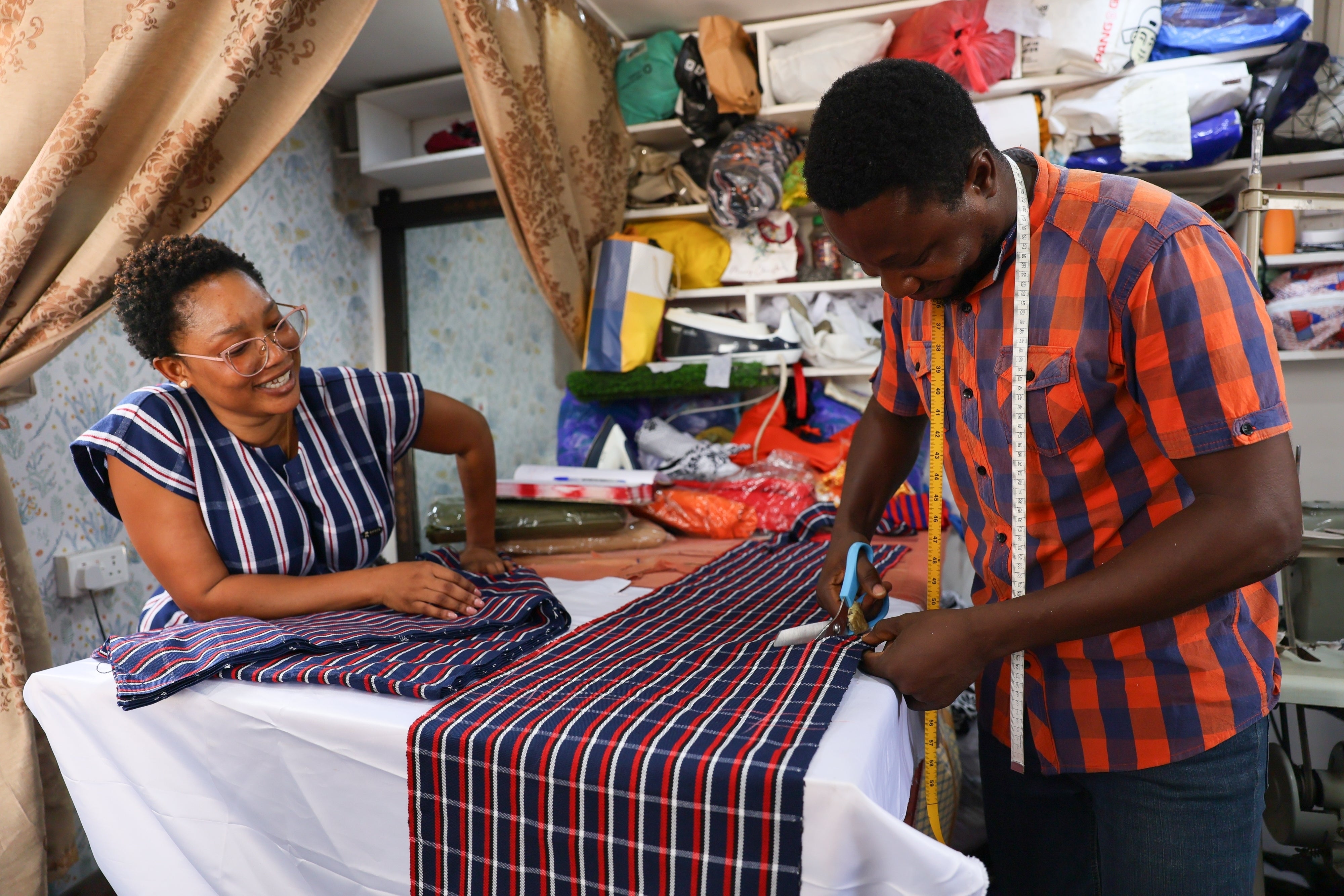 Perfectual Linnan, a fashion designer, interacts with a staff member at her workshop in Accra, Ghana