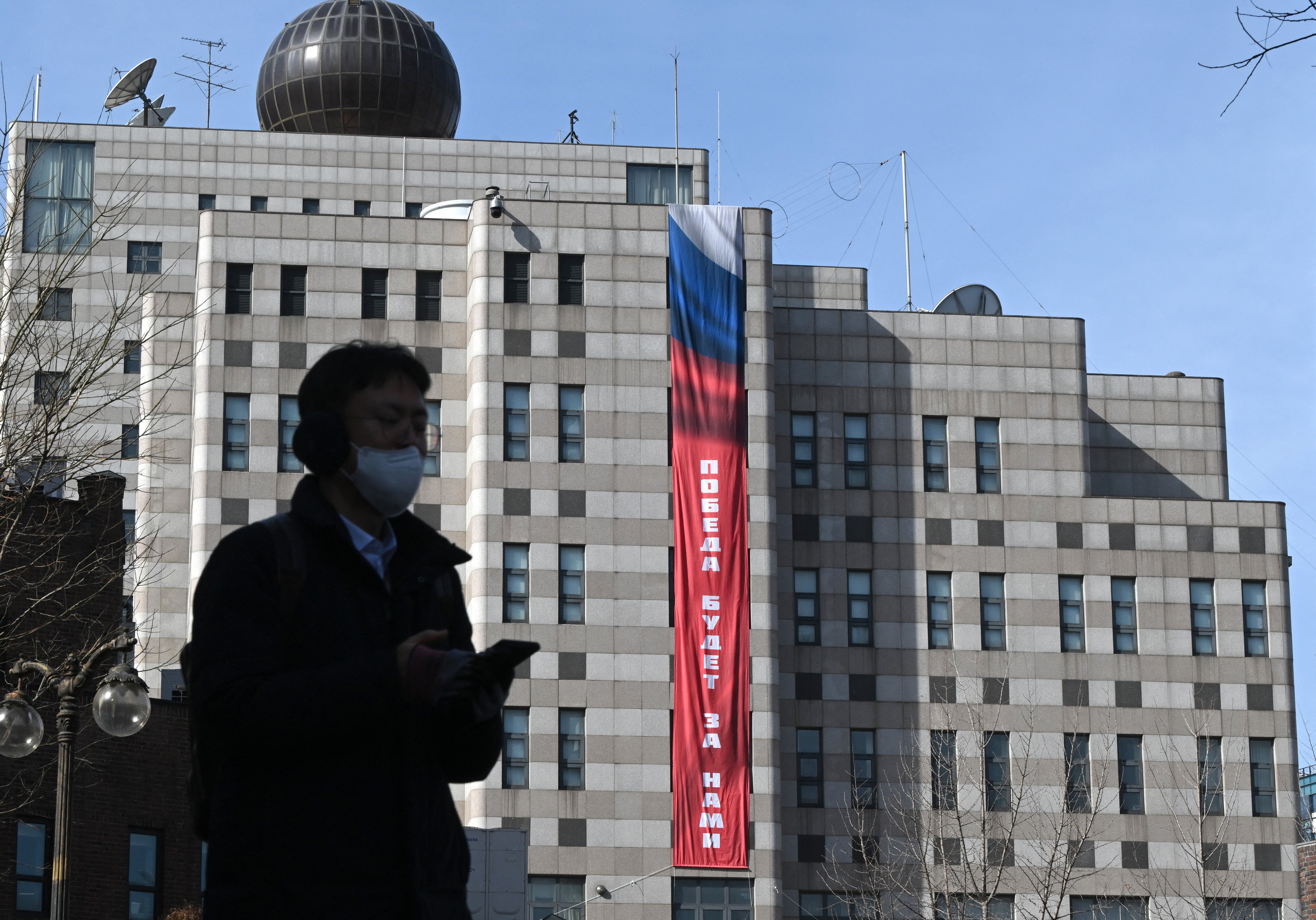 A man walks in front of the Russian embassy in Seoul where the banner is displayed