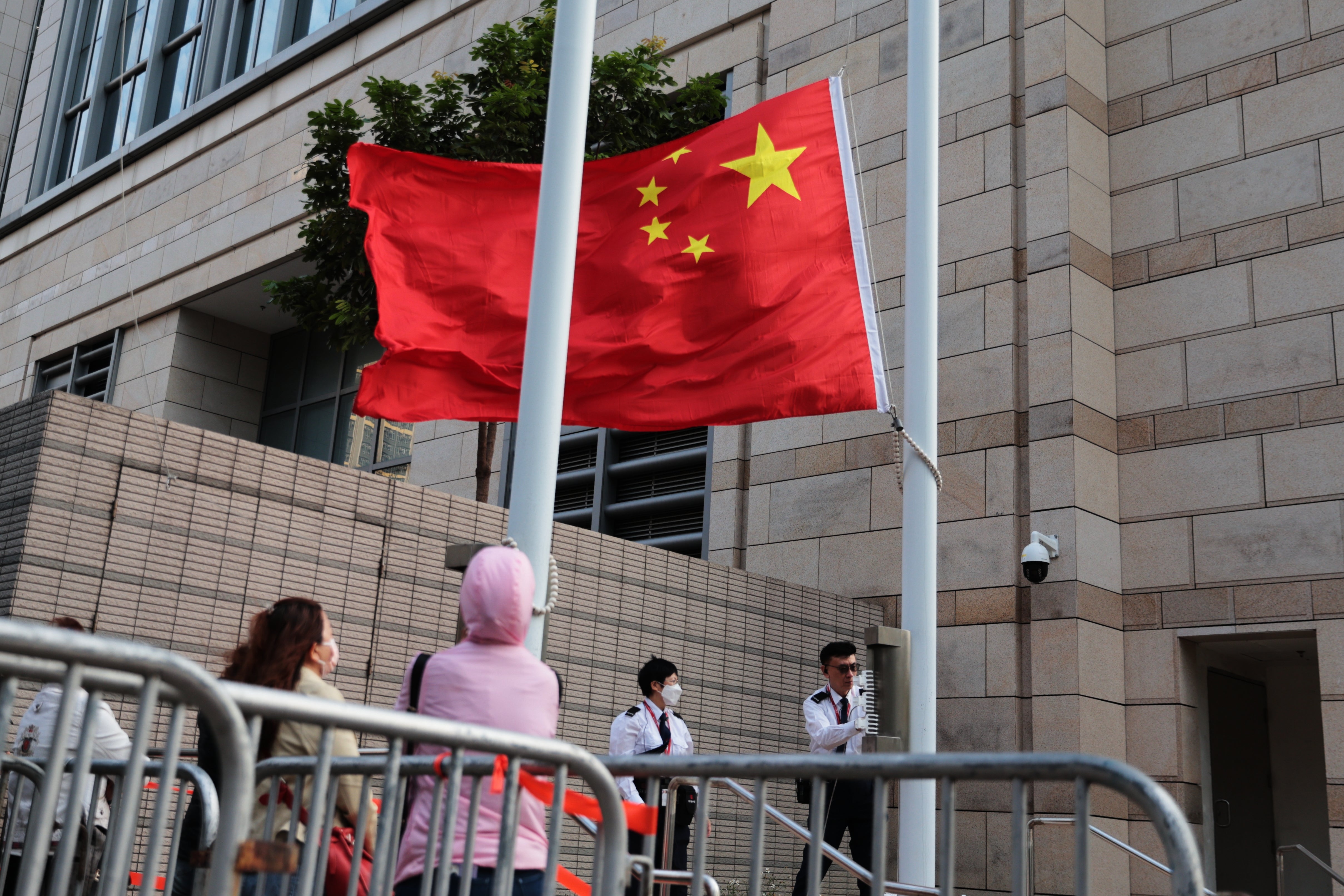Staff members of the West Kowloon Magistrates' Courts raise a China national flag outside West Kowloon Law Courts Building ahead of the national security appeal cases
