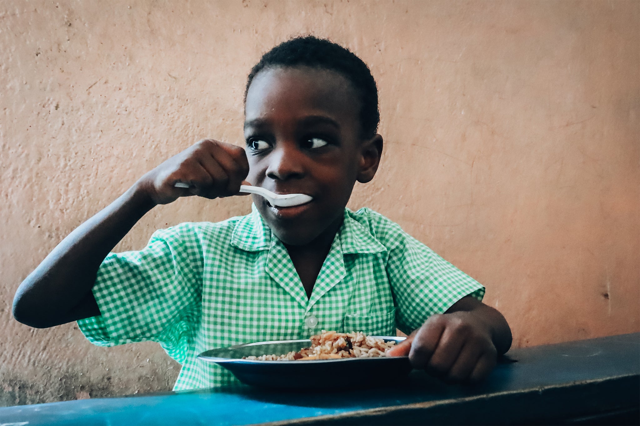 A kid eating Mary's Meals astatine schoolhouse successful Port-au-Prince