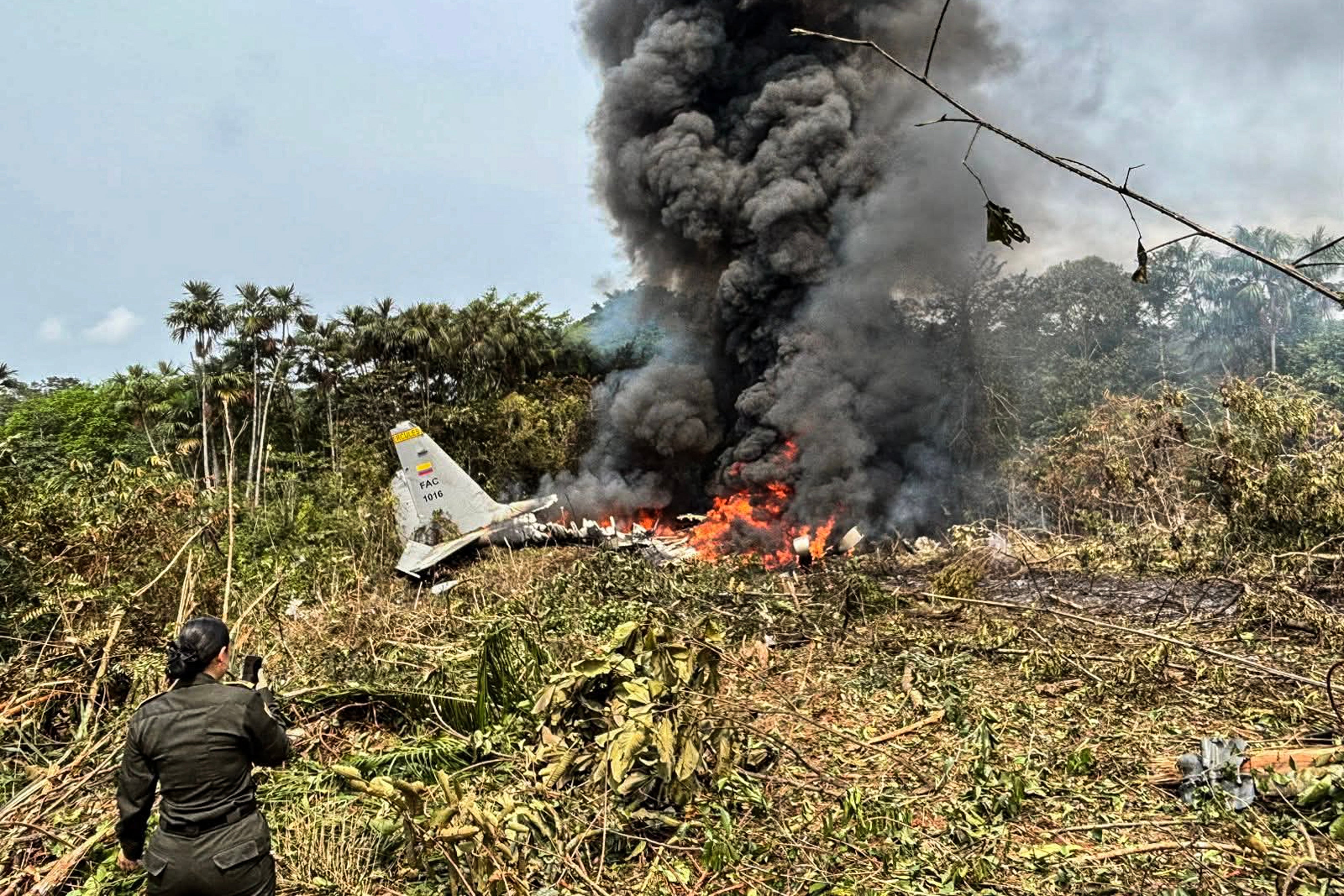 Flames and heavy achromatic fume emergence from an Air Force Hercules that collapsed during takeoff, arsenic a personnel of nan Colombian Police stands nearby, successful Puerto Leguizamo, Colombia
