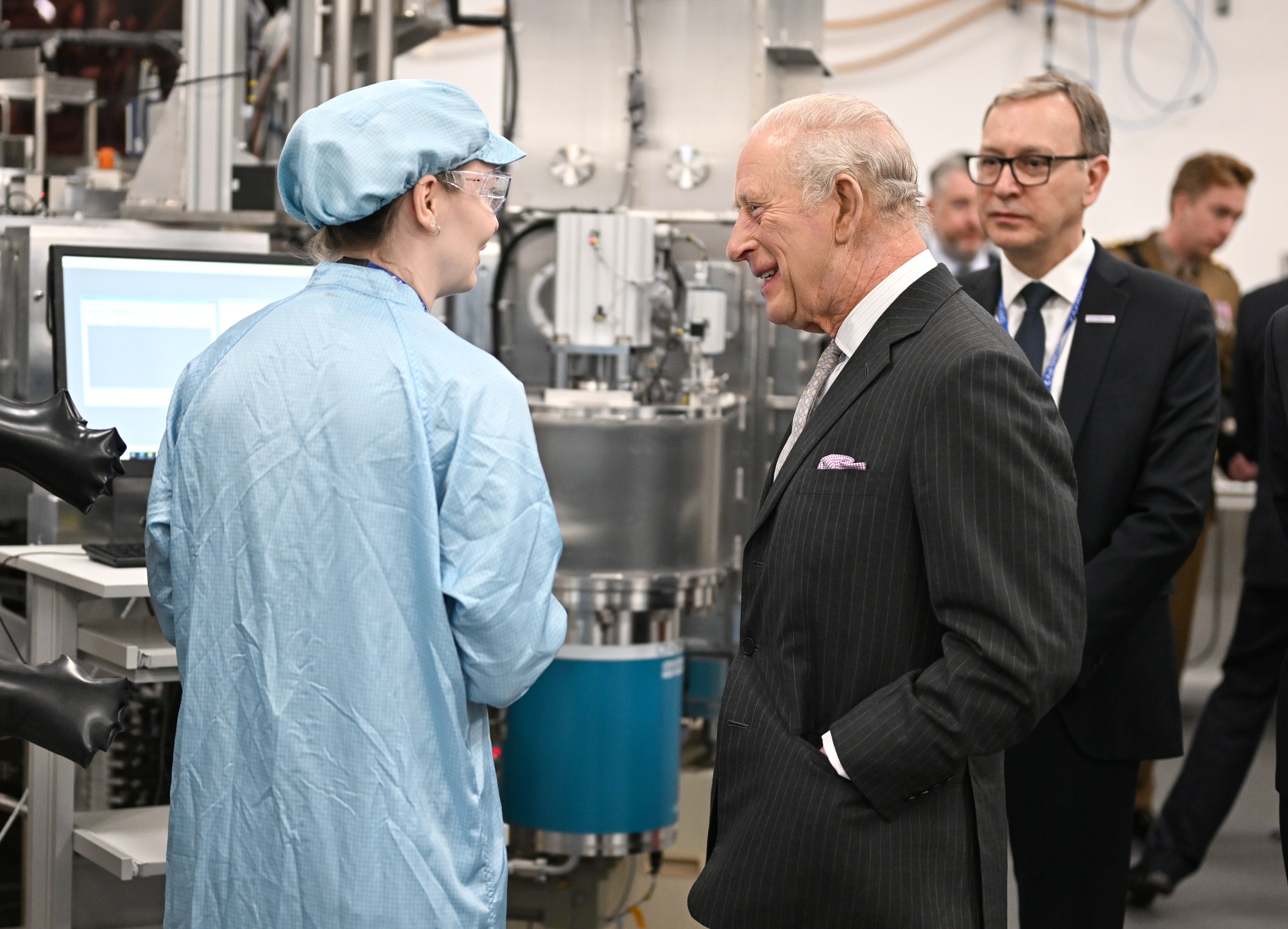 King Charles III speaks with a staff member during a visit to the plant