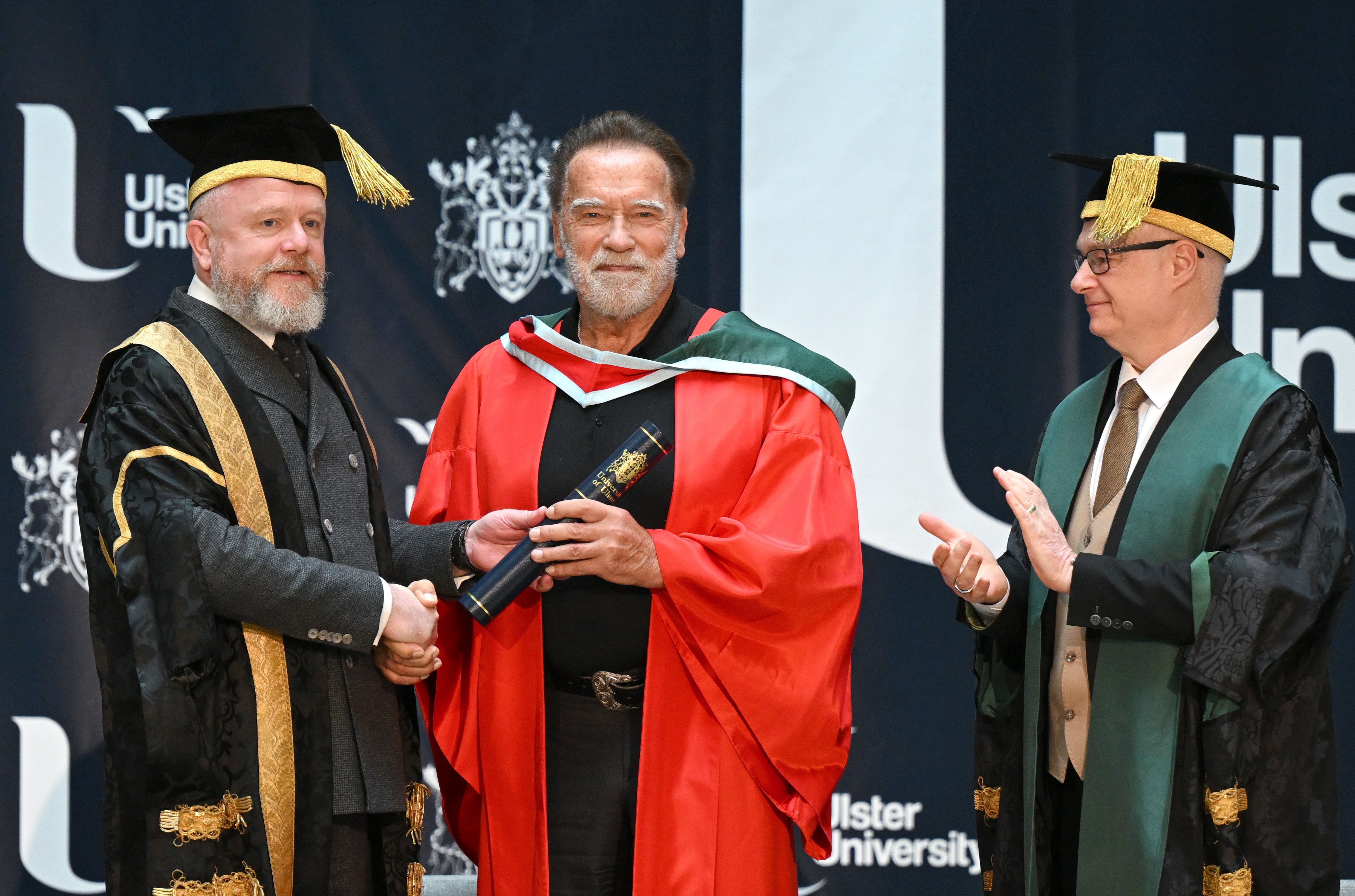 Arnold Schwarzenegger with Ulster University Chancellor Colin Davidson (L) and Professor Paul Bartholomew, Vice-Chancellor Ulster University (R) as he receives a honorary doctorate.