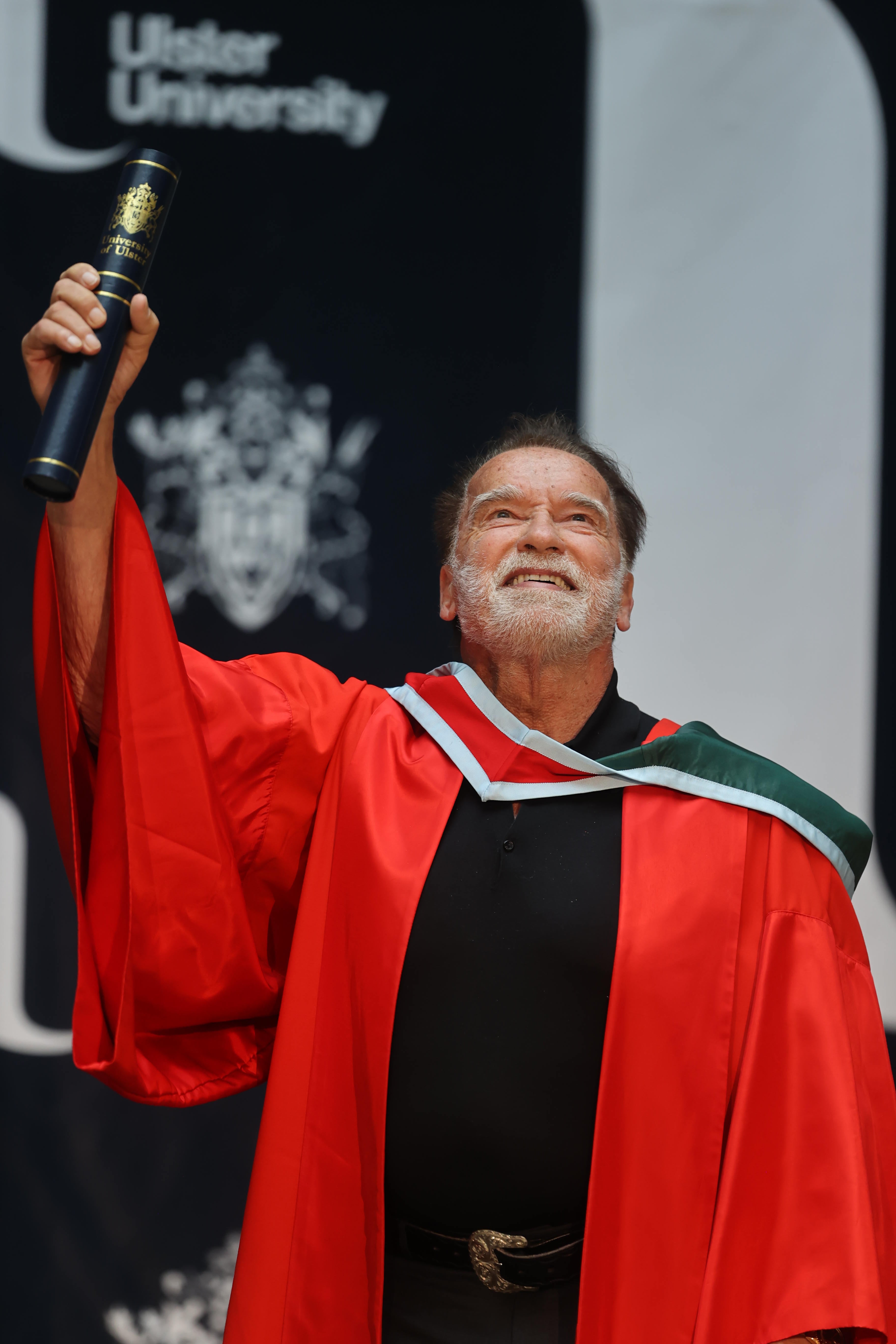 Arnold Schwarzenegger lifts his honorary doctorate presented to him by the Ulster University. (Liam McBurney/PA)