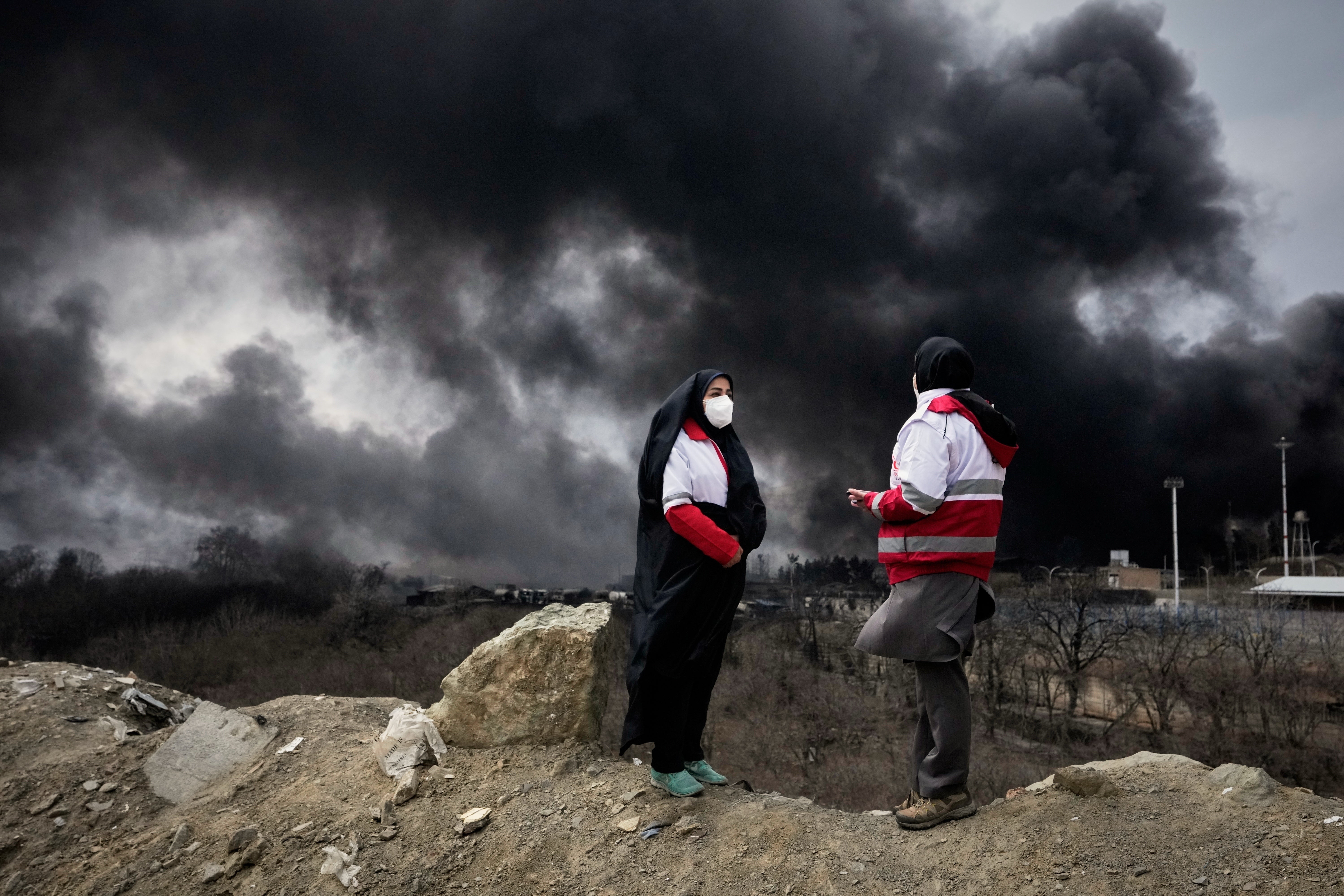 Two women from nan Iranian Red Crescent Society guidelines arsenic a heavy plume of fume from a U.S.-Israeli onslaught connected an lipid retention installation precocious Saturday rises into nan entity successful Tehran, Iran, Sunday, March 8, 2026. (AP Photo/Vahid Salemi, File)