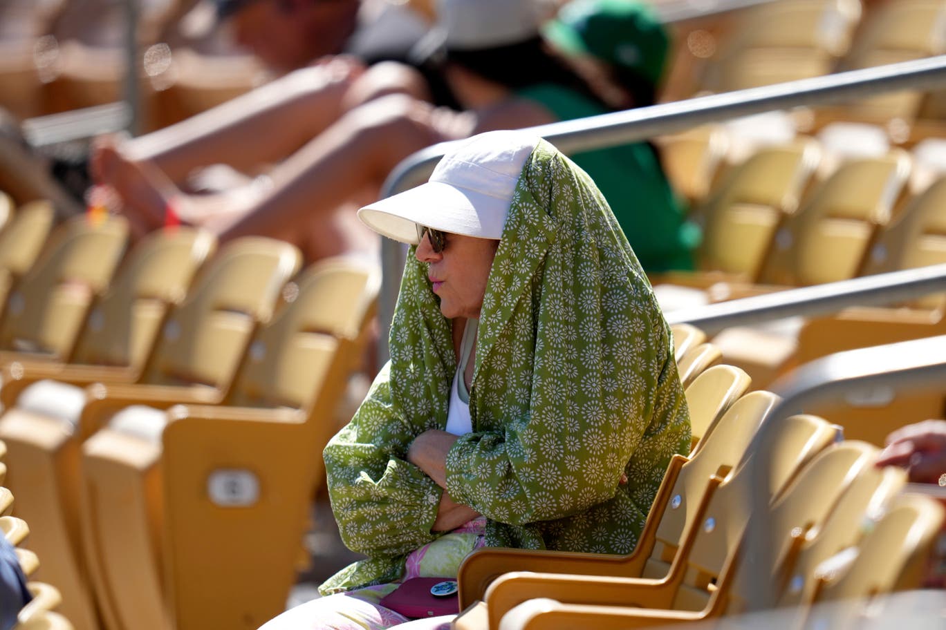 A baseball fan tries to shield from the sun during the fourth inning of a spring training baseball game between the Chicago White Sox and the Athletics.