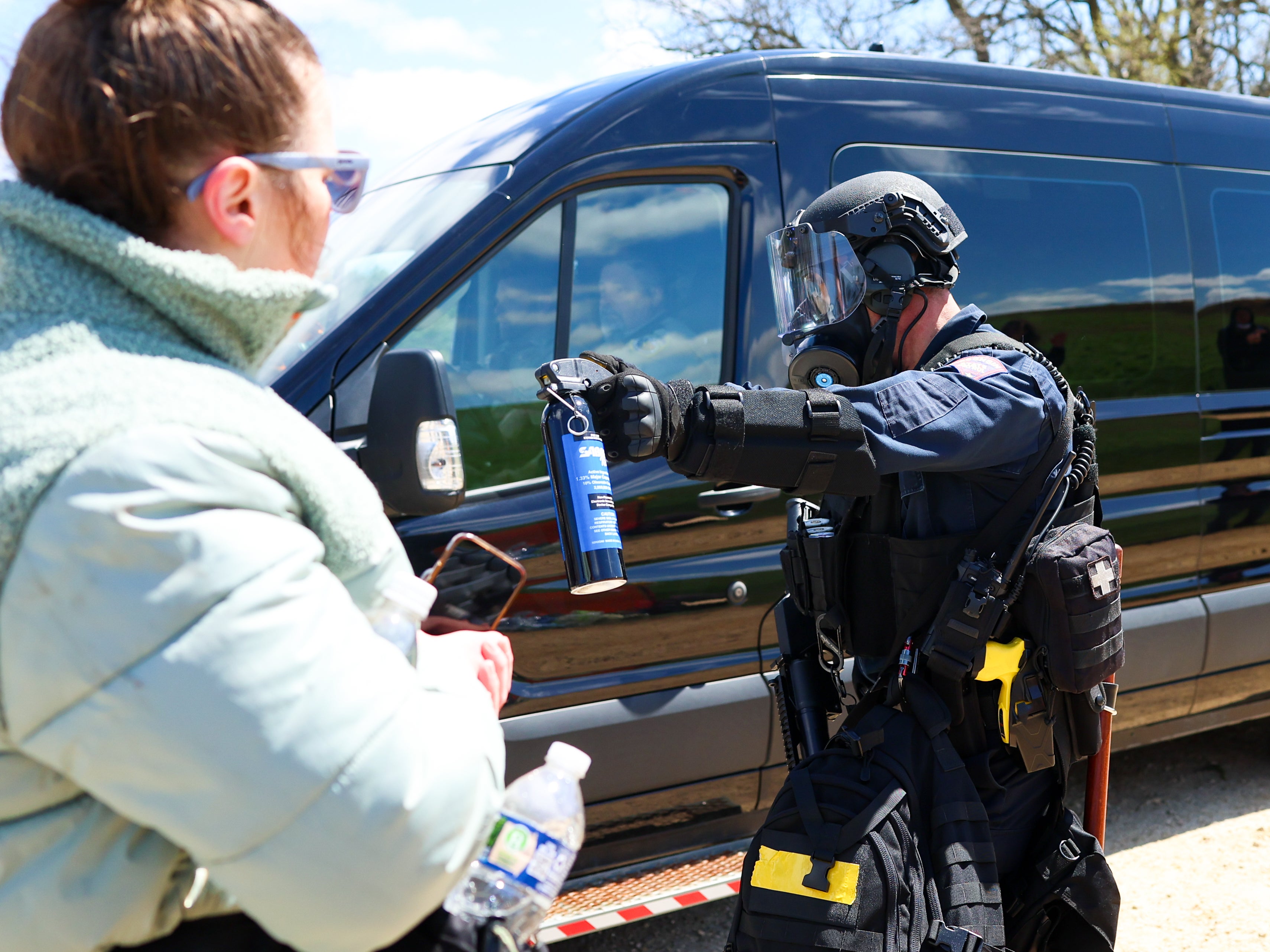A Wisconsin State Patrol officer points a can of mace at activists as officers make way for a van to leave the grounds of Ridglan Farms beagle breeding and research facility