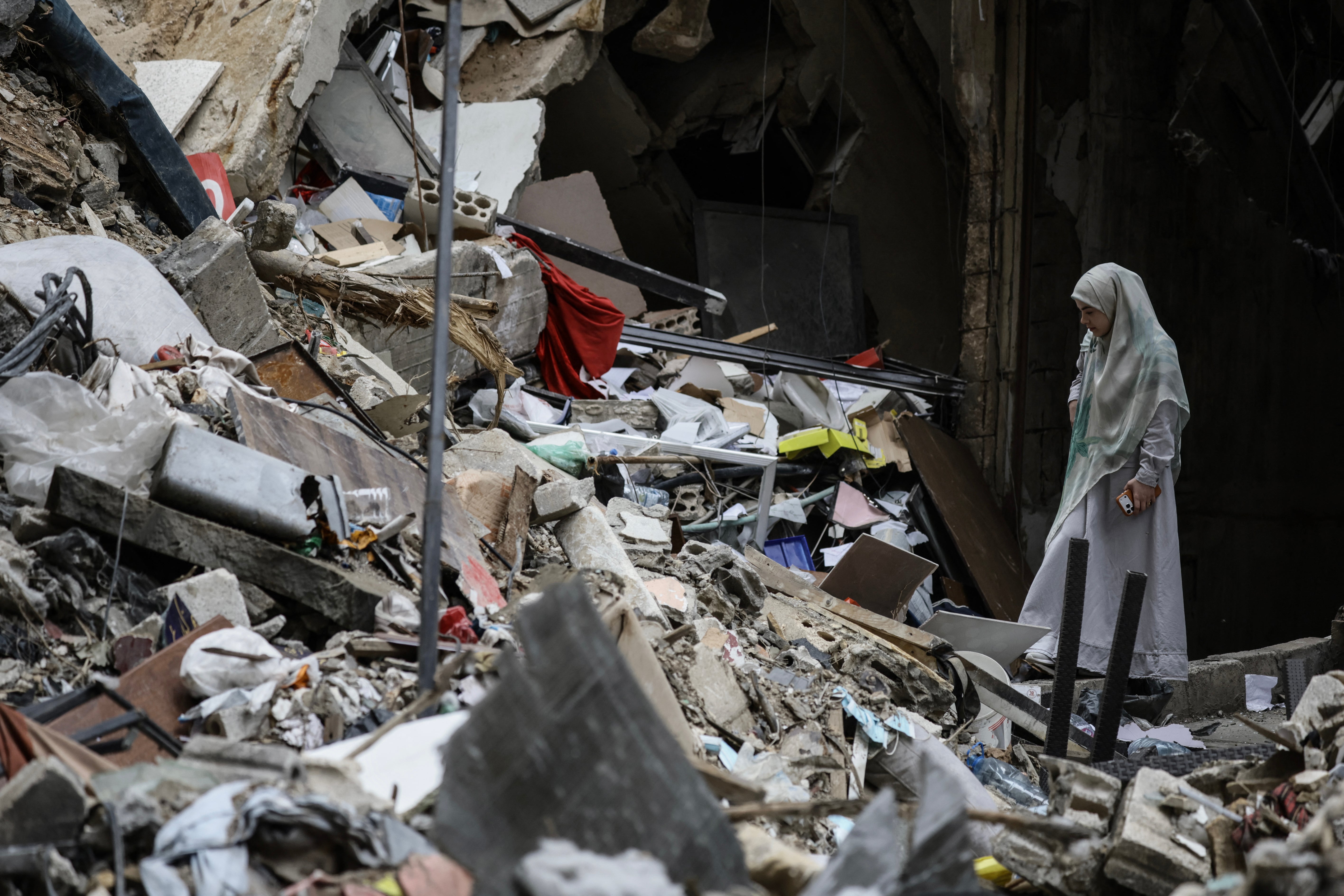 A woman stands amid the debris of a destroyed building in the Haret Hreik area of south Beirut during a media tour organised by Iran-backed militant group Hezbollah on 20 April