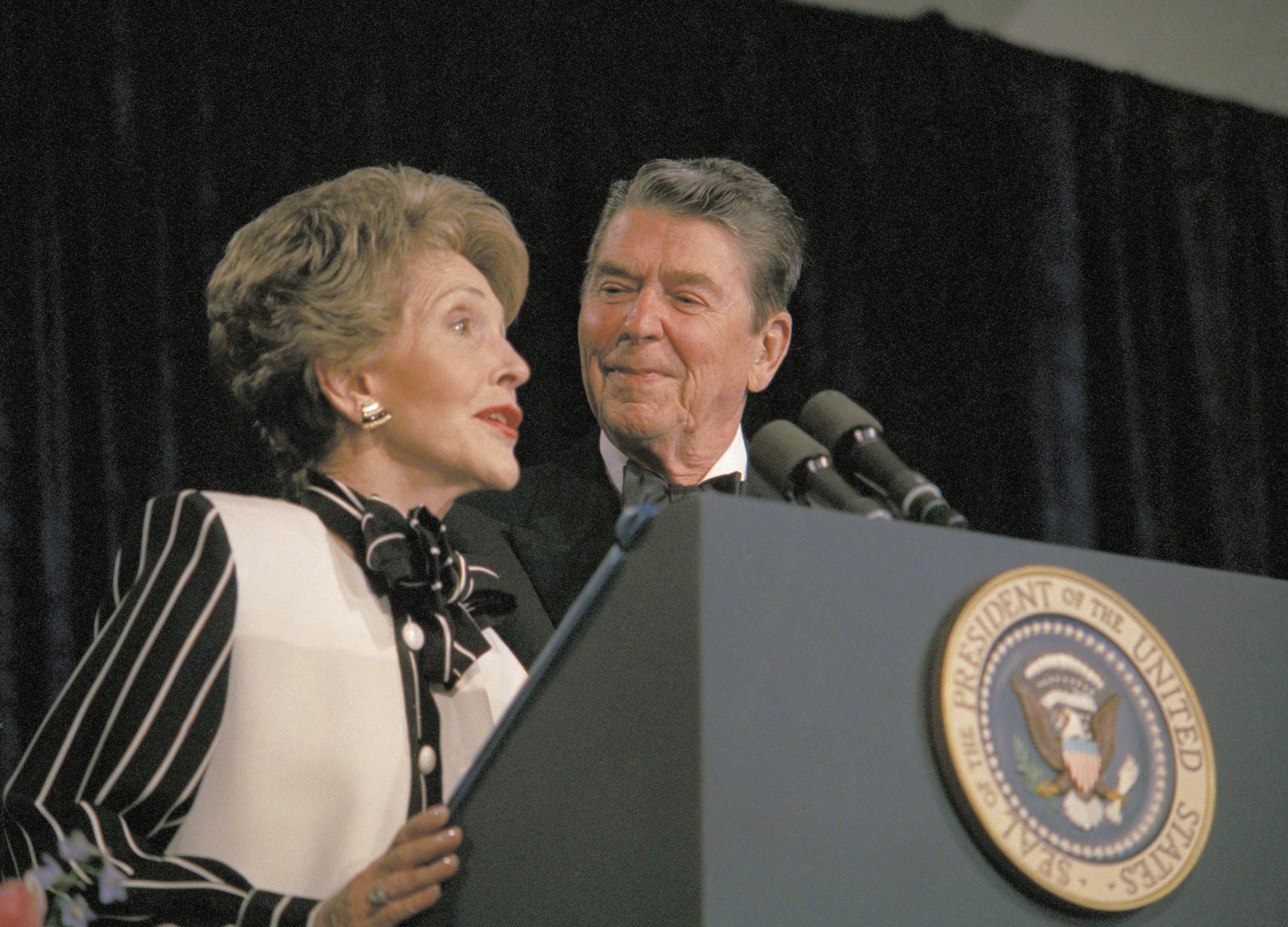 President Ronald Reagan watches arsenic first woman Nancy Reagan comments from nan podium during nan White House Correspondents' Association yearly meal 1983