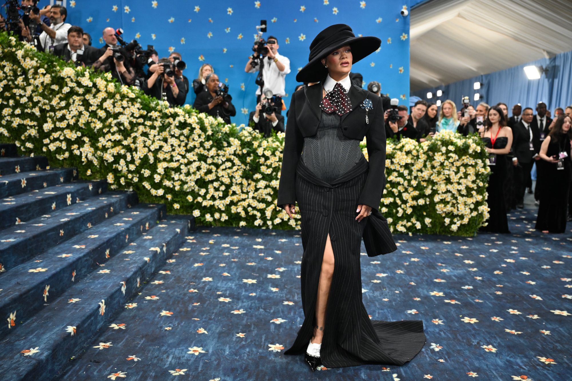 Rihanna on the Met Gala carpet in 2025. The midnight blue background and yellow daffodils were hand-painted on the 2025 Met Gala red carpet after it was constructed over 90 days in India