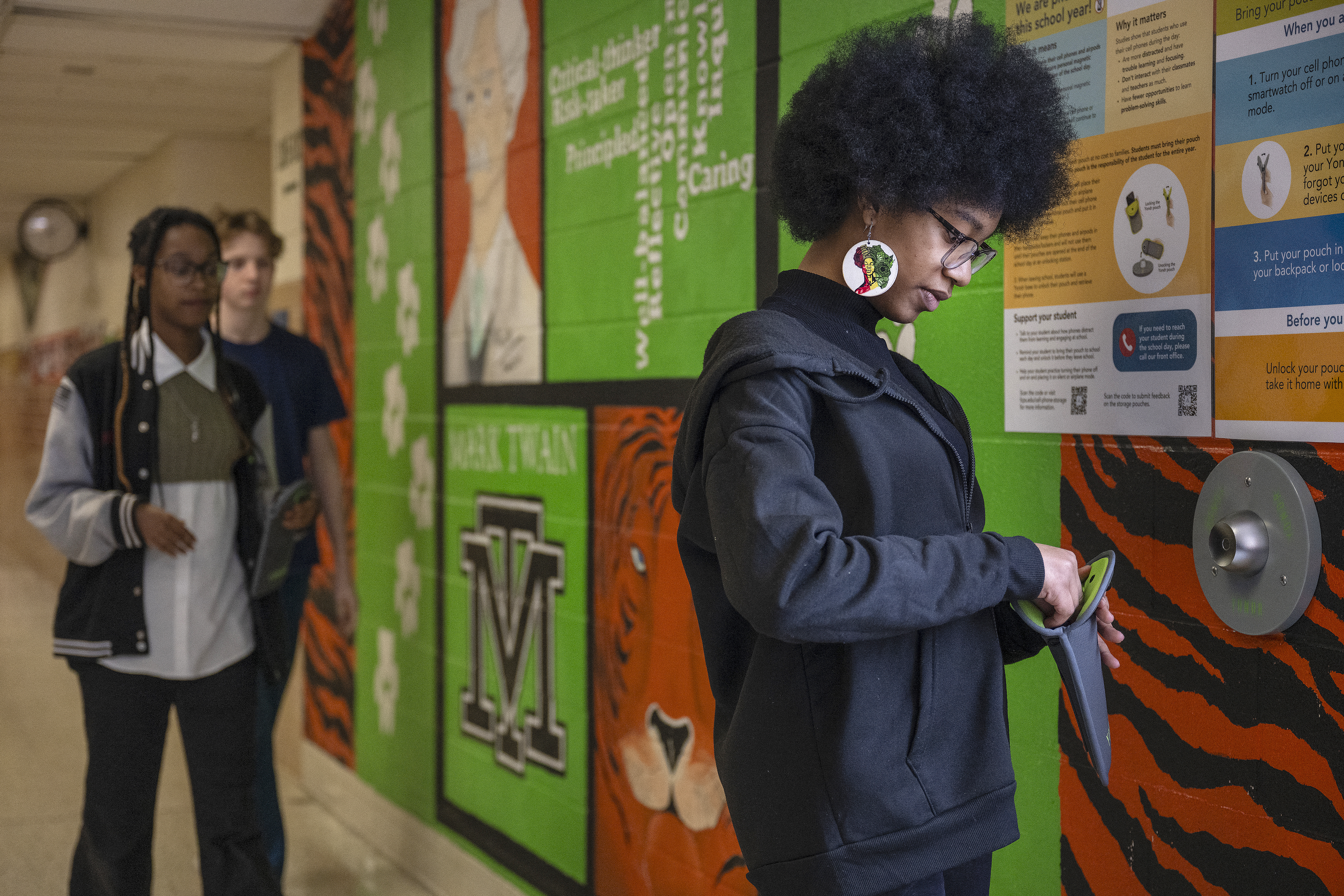 Middle school students unlock their Yondr cell phone pouches at the end of the day last March at Mark Twain Middle School in Alexandria, Virginia. New research shows the pouches can help cut back on screen time during the school day - but have little effect on improving academic performance