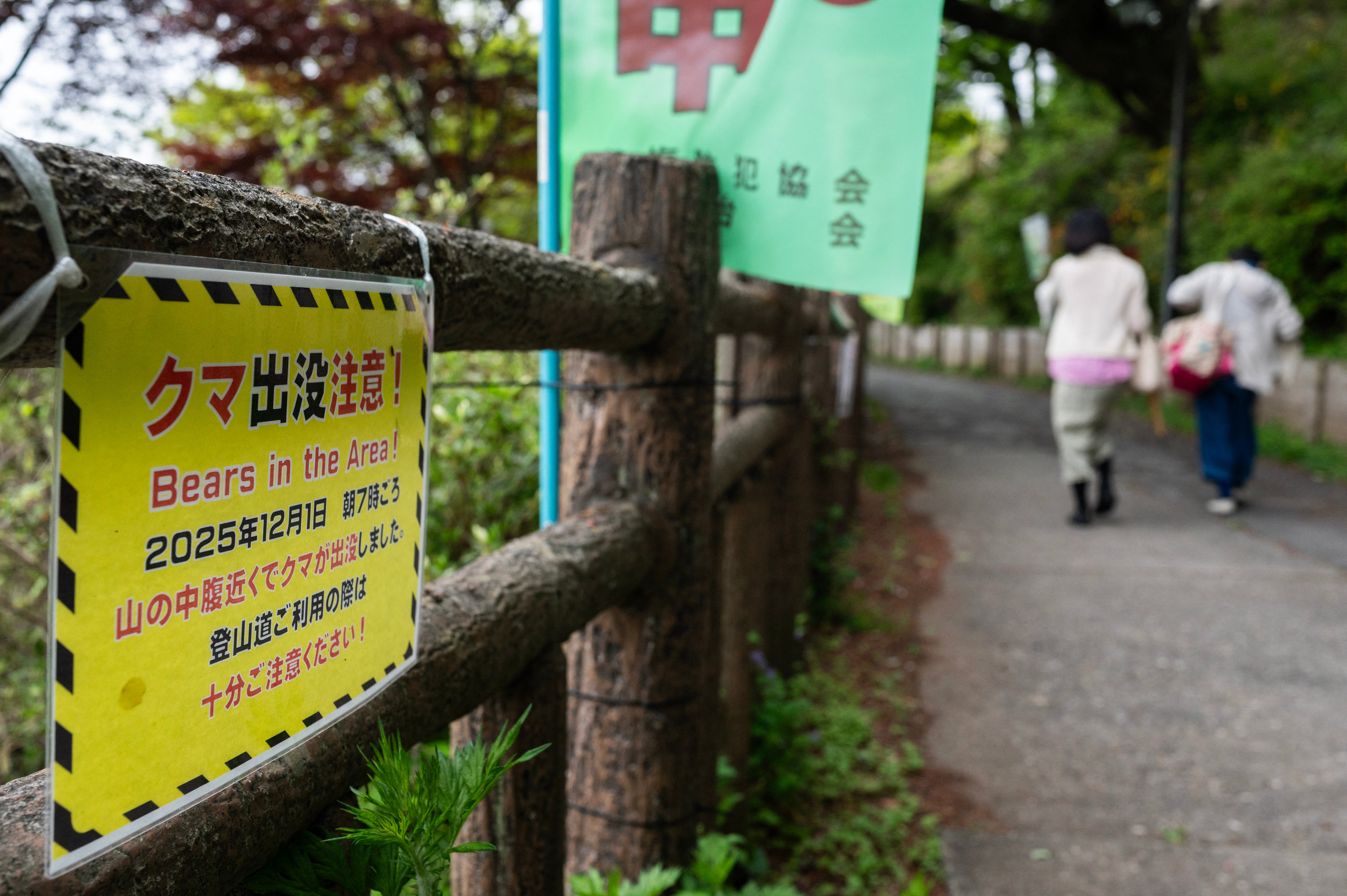 Hikers walk past a sign warning of bears in the area in Ome, Tokyo