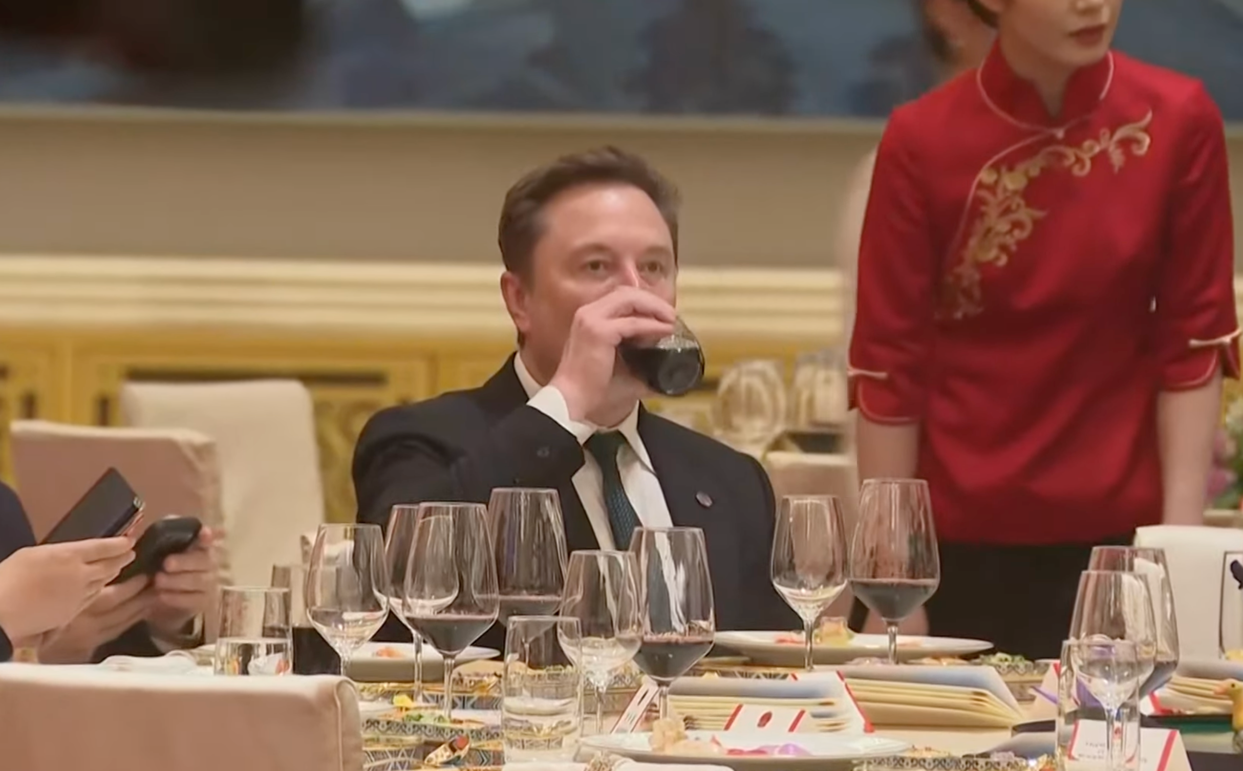 Musk taking a swig of a red drink