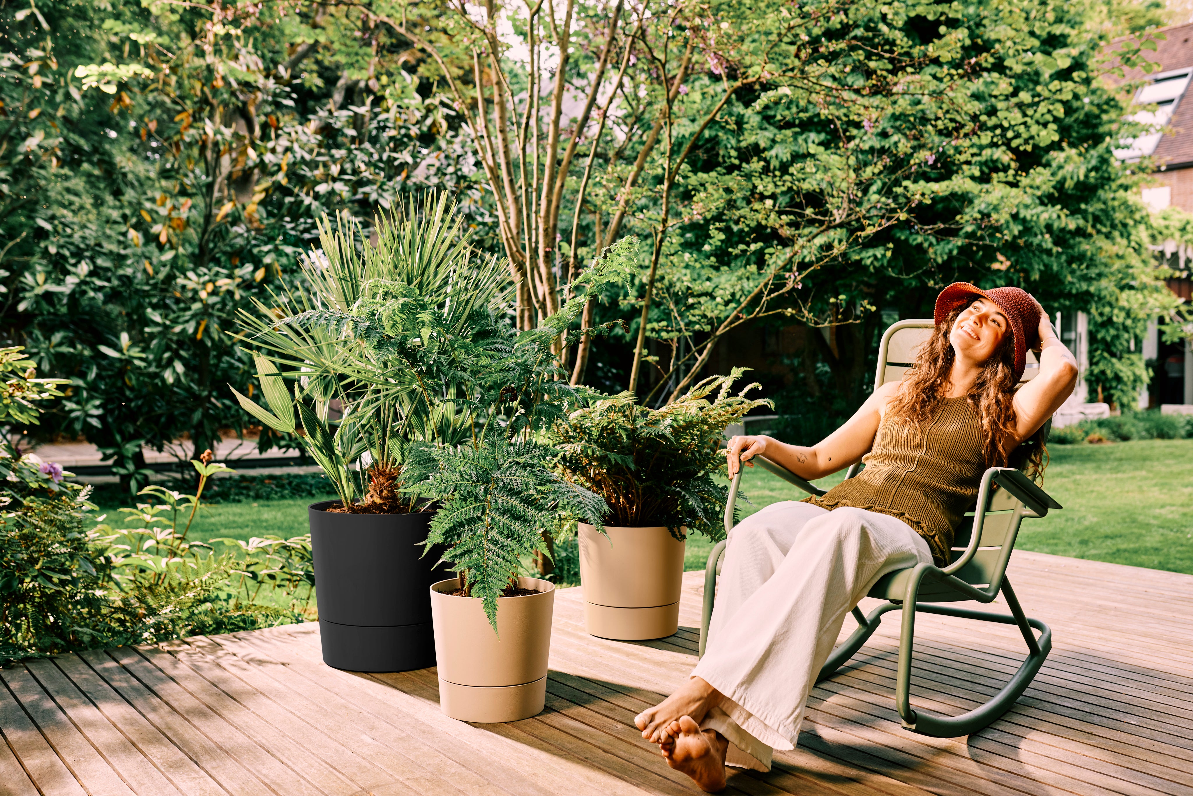 A woman on garden decking with Elho foss pots with reservoirs