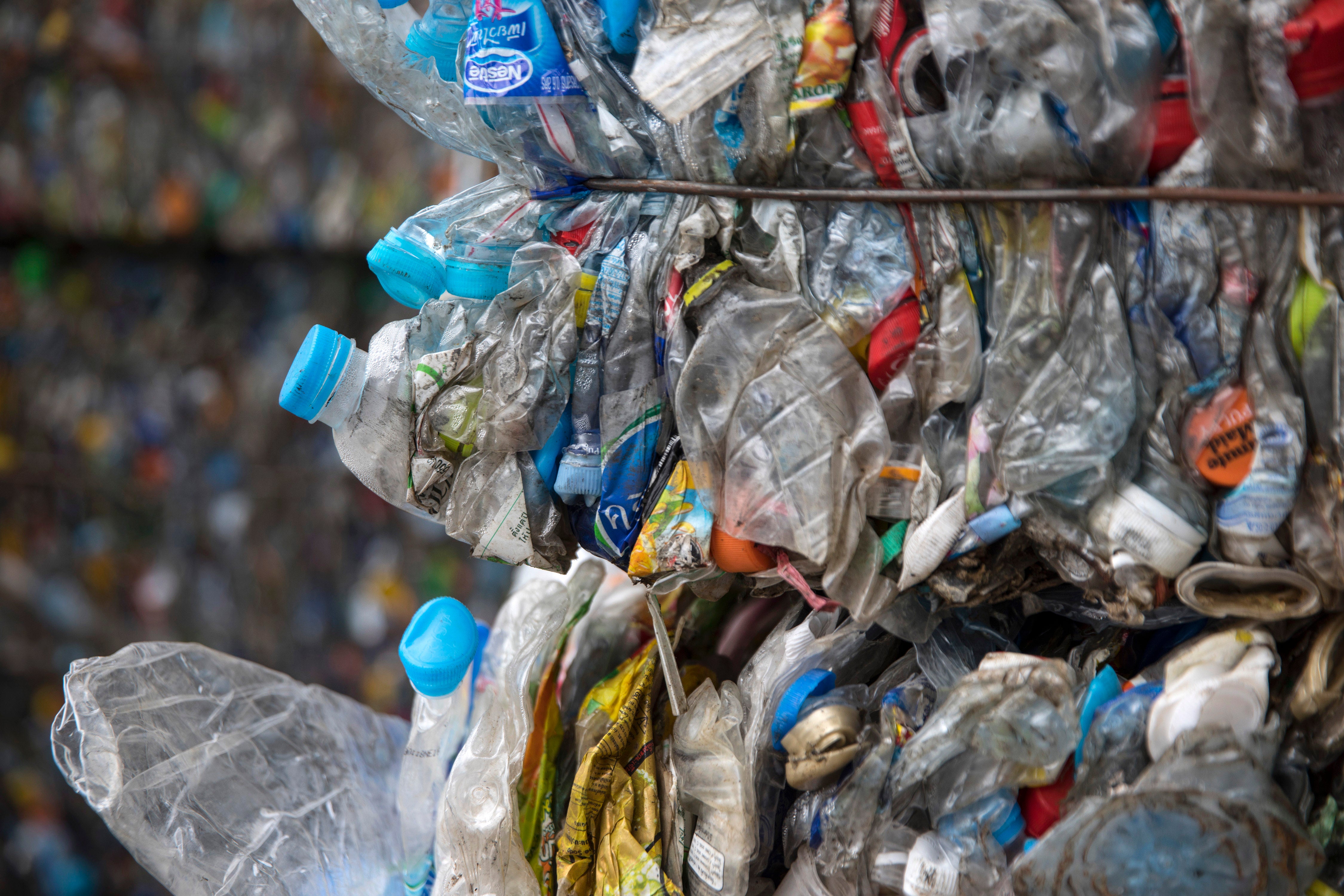 Stack flattened plastic bottles in bales for recycling.