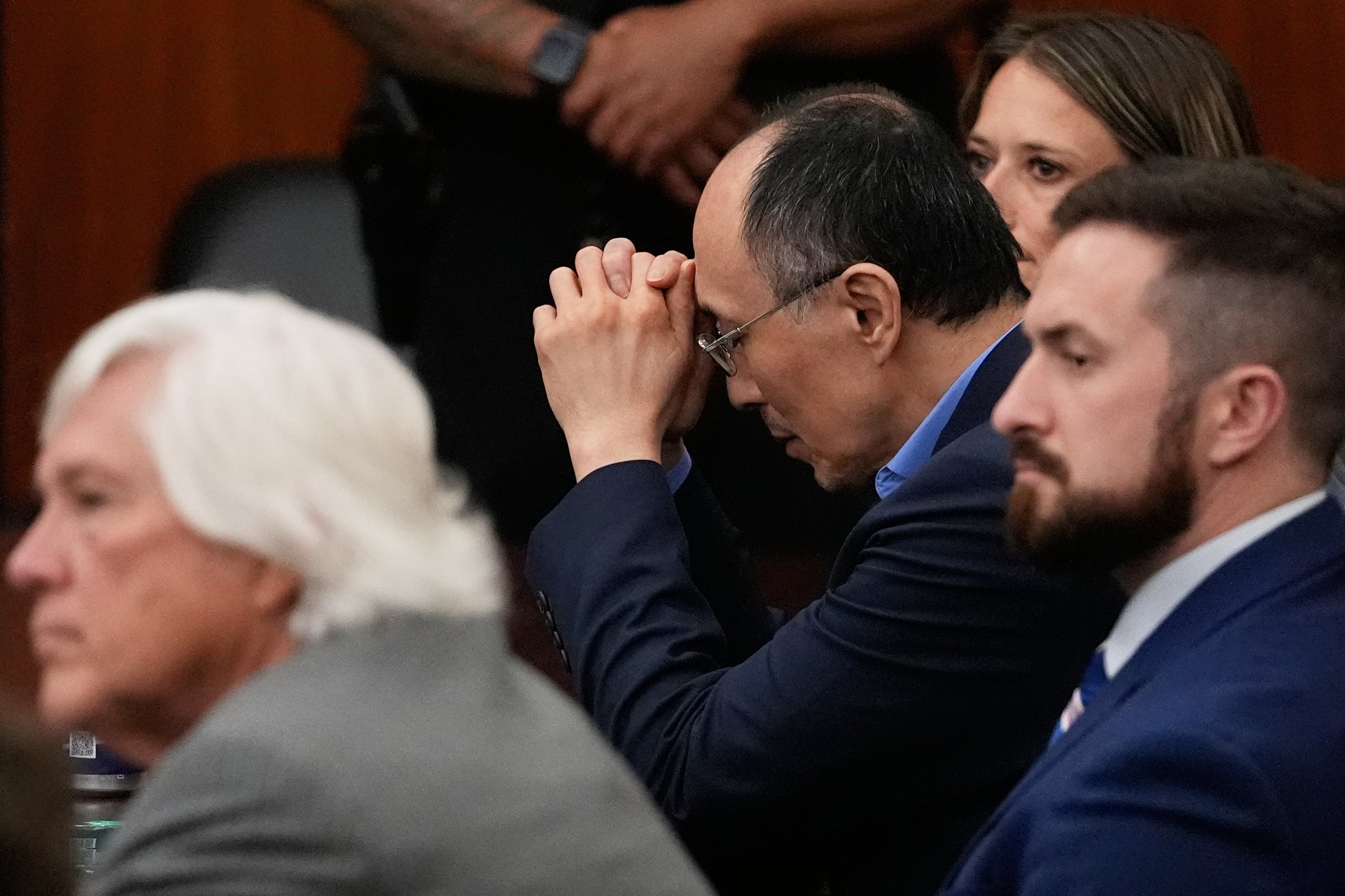 Chow sat silently frozen before slowly bowing his head onto his interlocked hands