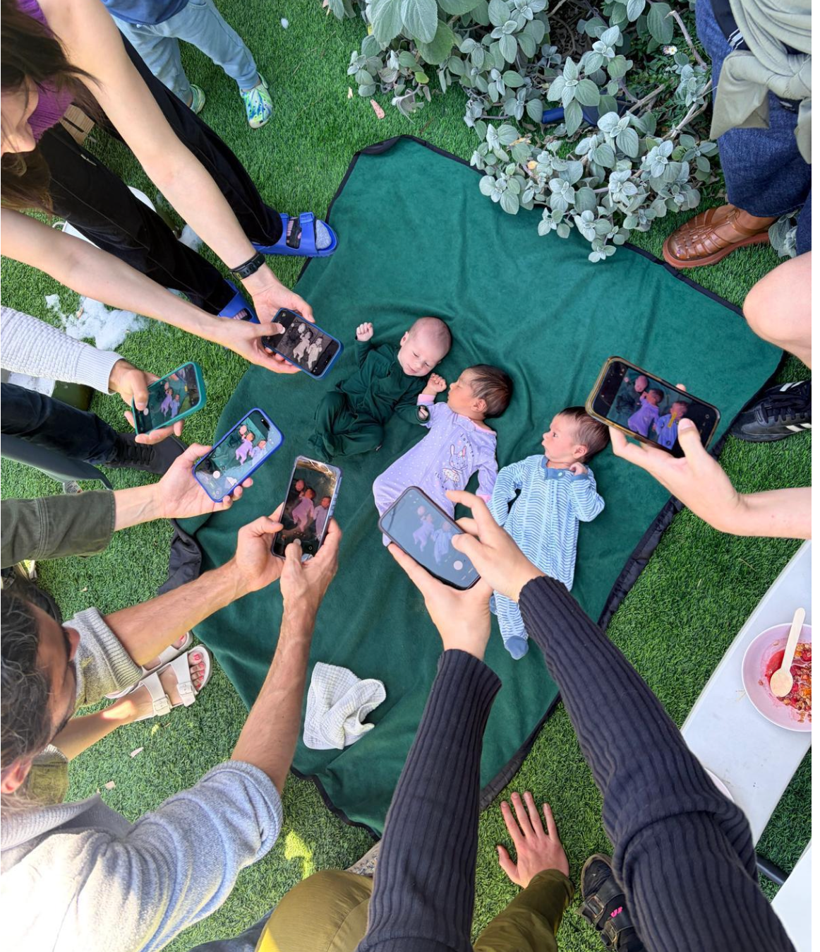 When three infants were born within a 15-day window, the entire 20-person community surrounded them on a blanket for a celebratory ‘paparazzi’ shot