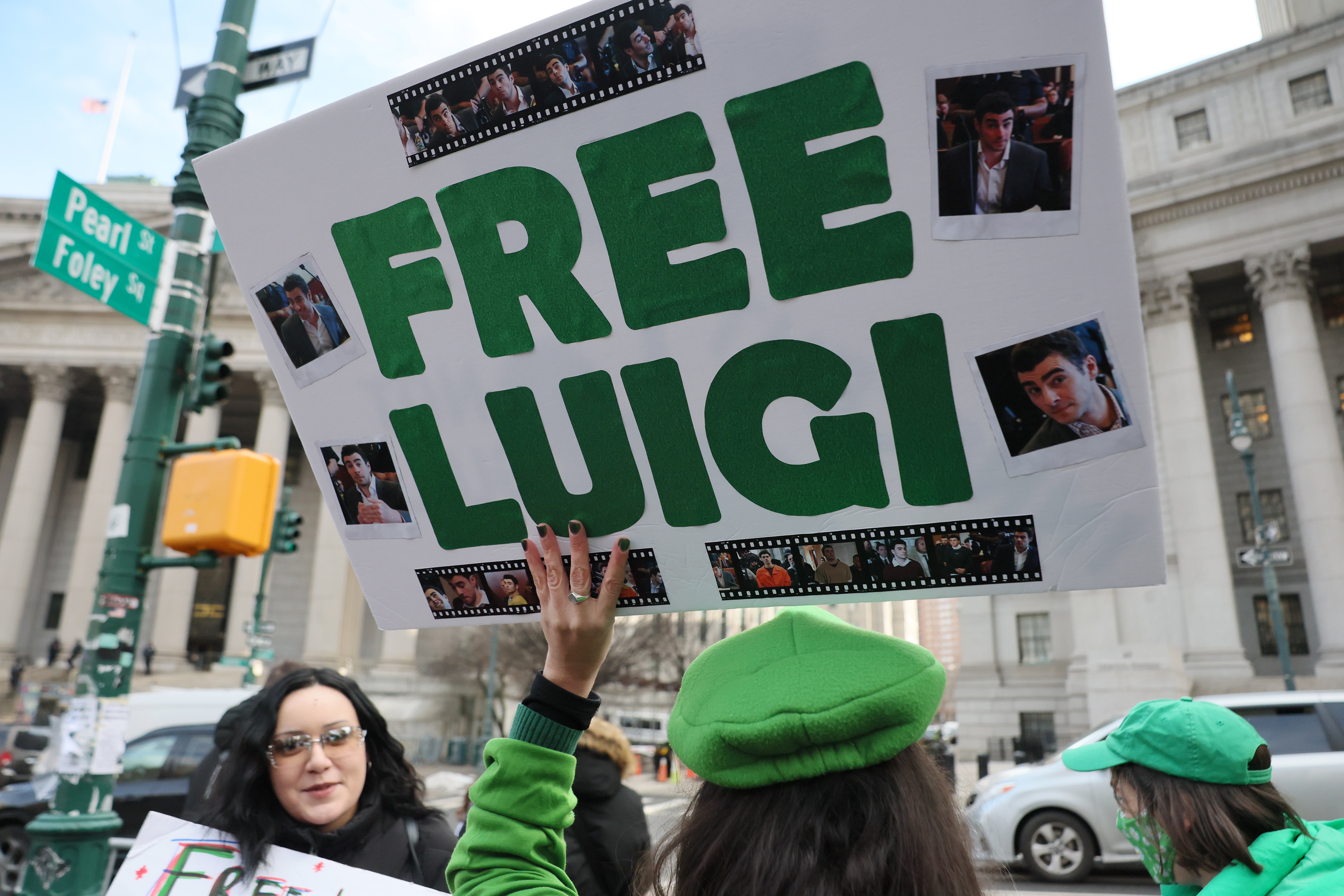 Fans of Luigi Mangione attend his pretrial hearings wearing Luigi merchandise and holding supportive signs outside of the courthouse