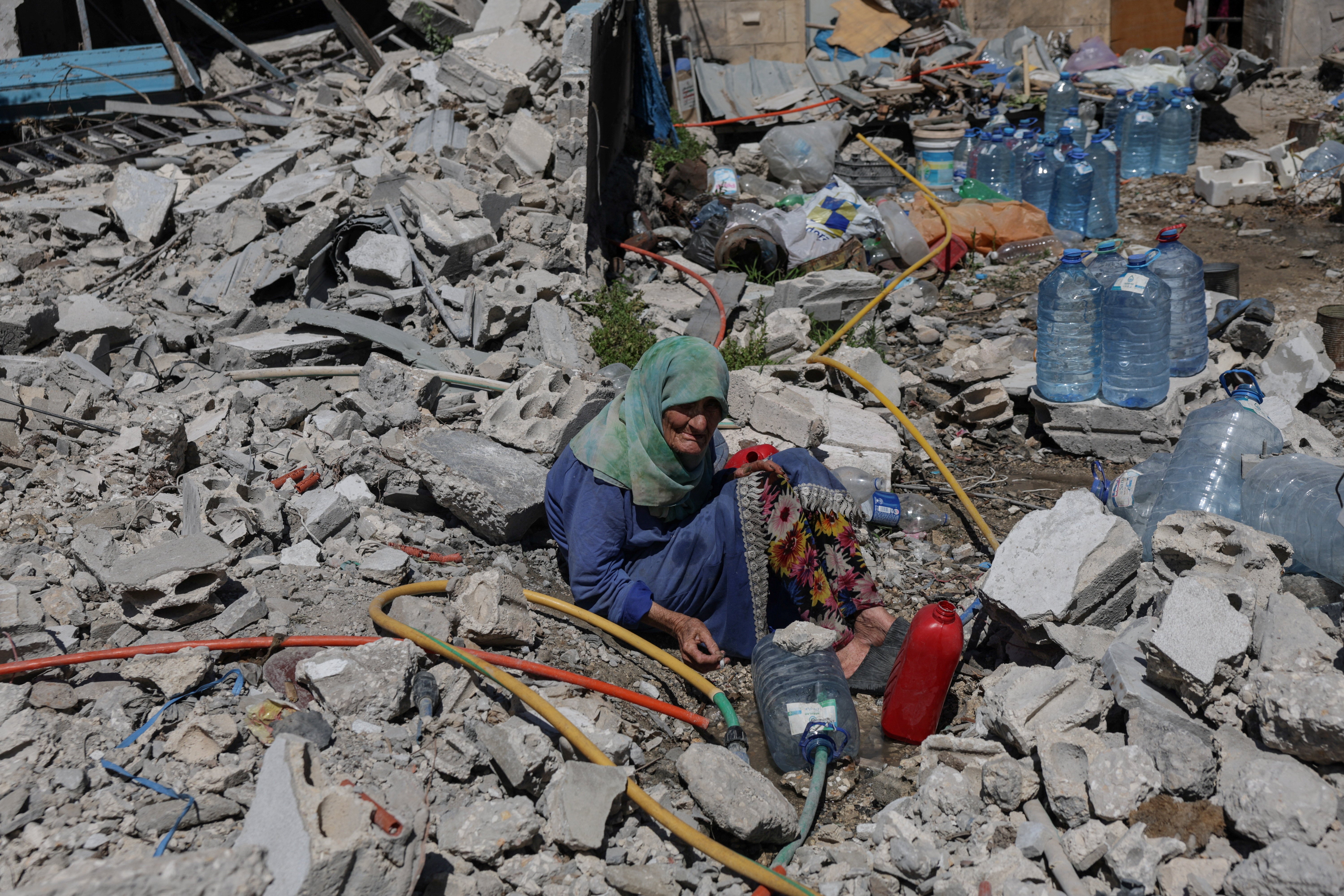 Khadija Amara, whom section residents said had not near her home, fills a jerrycan pinch h2o arsenic she sits among nan rubble of a house, which was damaged by an Israeli strike, successful Qlaileh successful nan Tyre district, confederate Lebanon