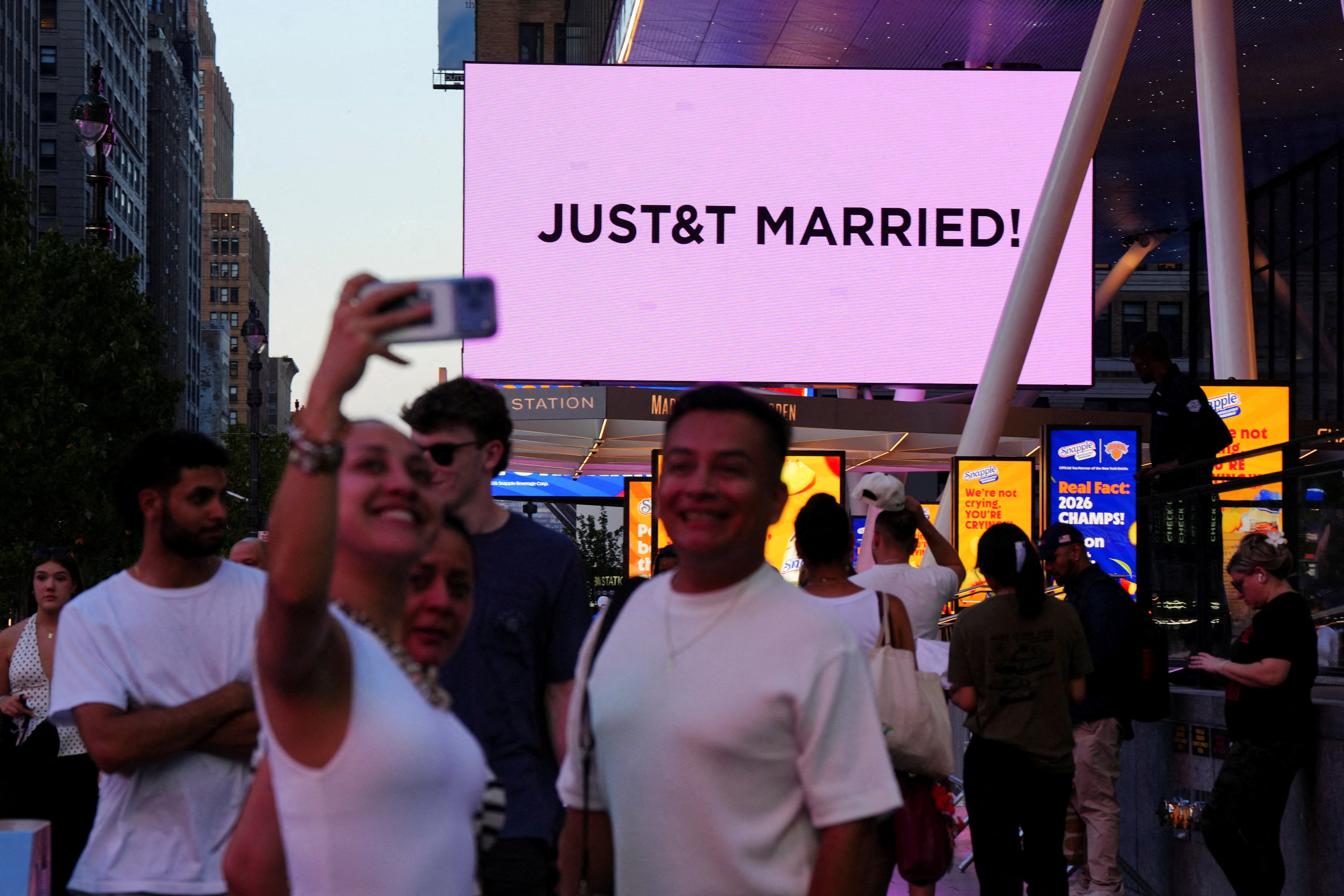 Fans take selfies outside Swift and Kelce’s wedding as the new is announced on giant screens outside MSG