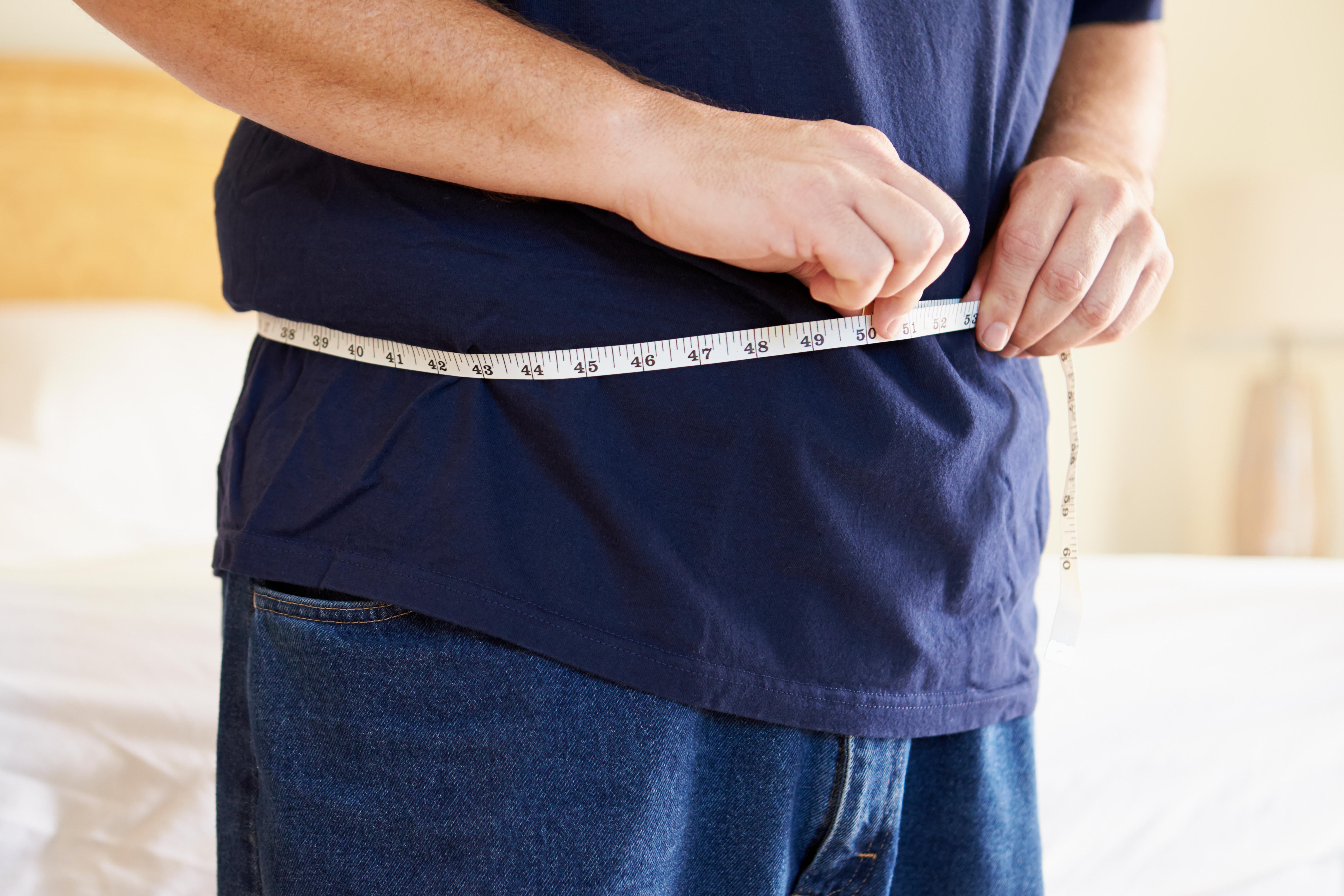 Close up of overweight man measuring waist (Alamy/PA)