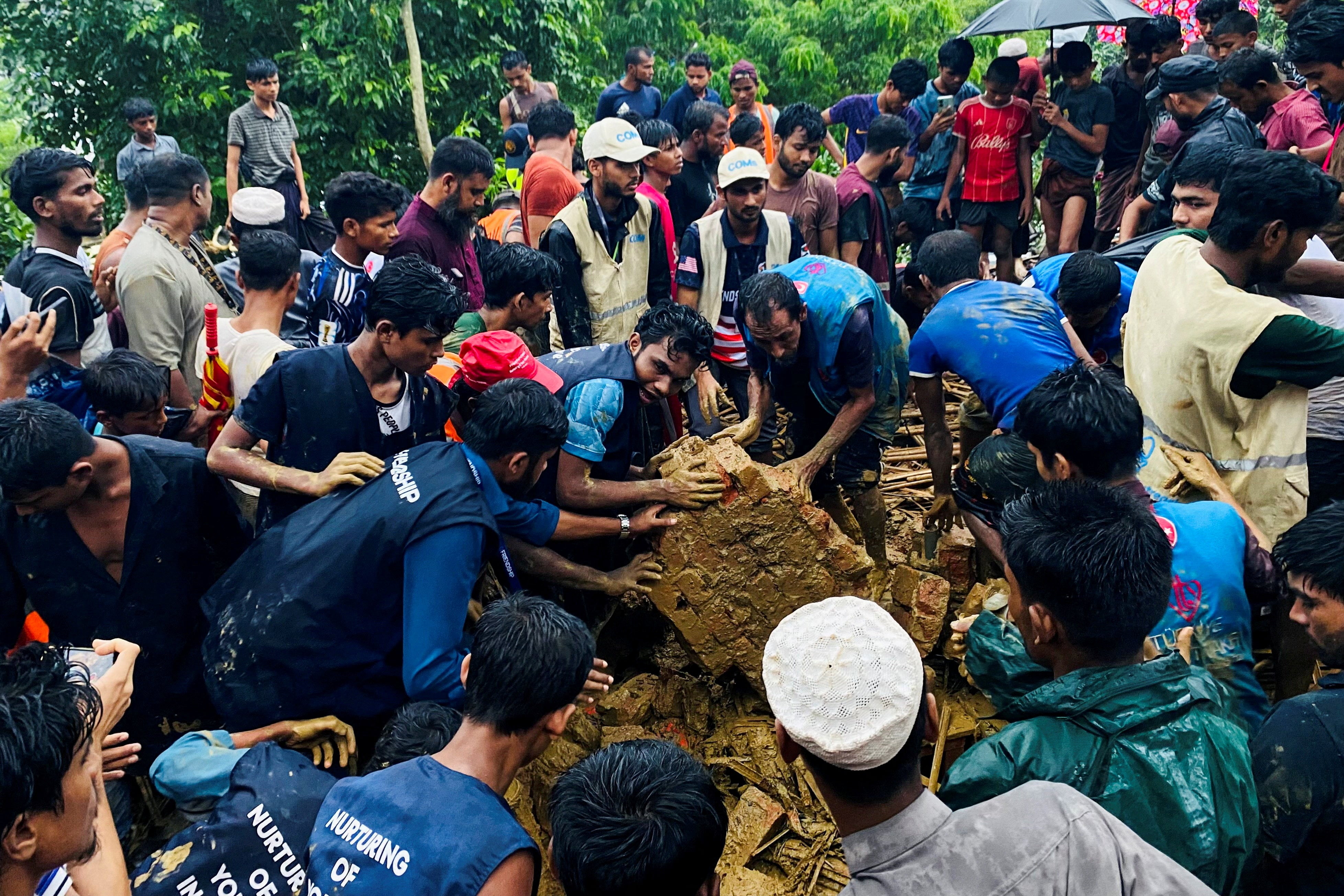 Rohingya refugees useful to rescue victims from a landslide spot astatine a Rohingya Refugee Camp pursuing continuous torrential rain, successful Cox’s Bazar, Bangladesh, July 8, 2026