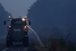 Poljoprivredni radnik vozi traktor dok vlaži vegetaciju uz cestu kao preventivnu mjeru za zaustavljanje širenja šumskih požara, dok šumski požari bjesne regijom Gironde usred pogoršanih sušnih uvjeta nakon toplinskog vala i nestašice vode u većem dijelu Francuske, u blizini Sainte-Helene, Francuska