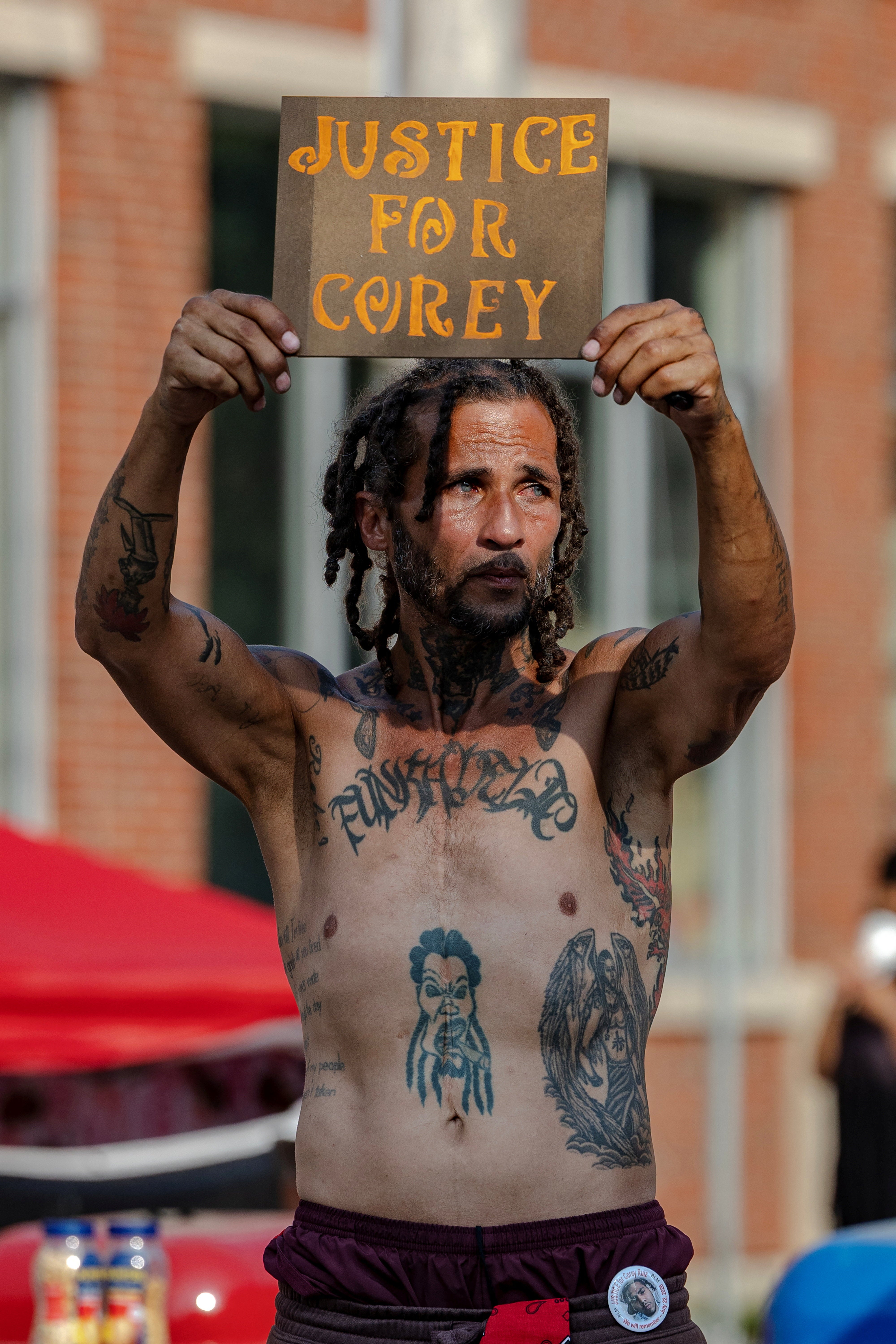 A mourner holds up a motion astatine a memorial for Corey Ruiz astatine nan tract wherever he was changeable and killed by constabulary connected July 22, successful Madison