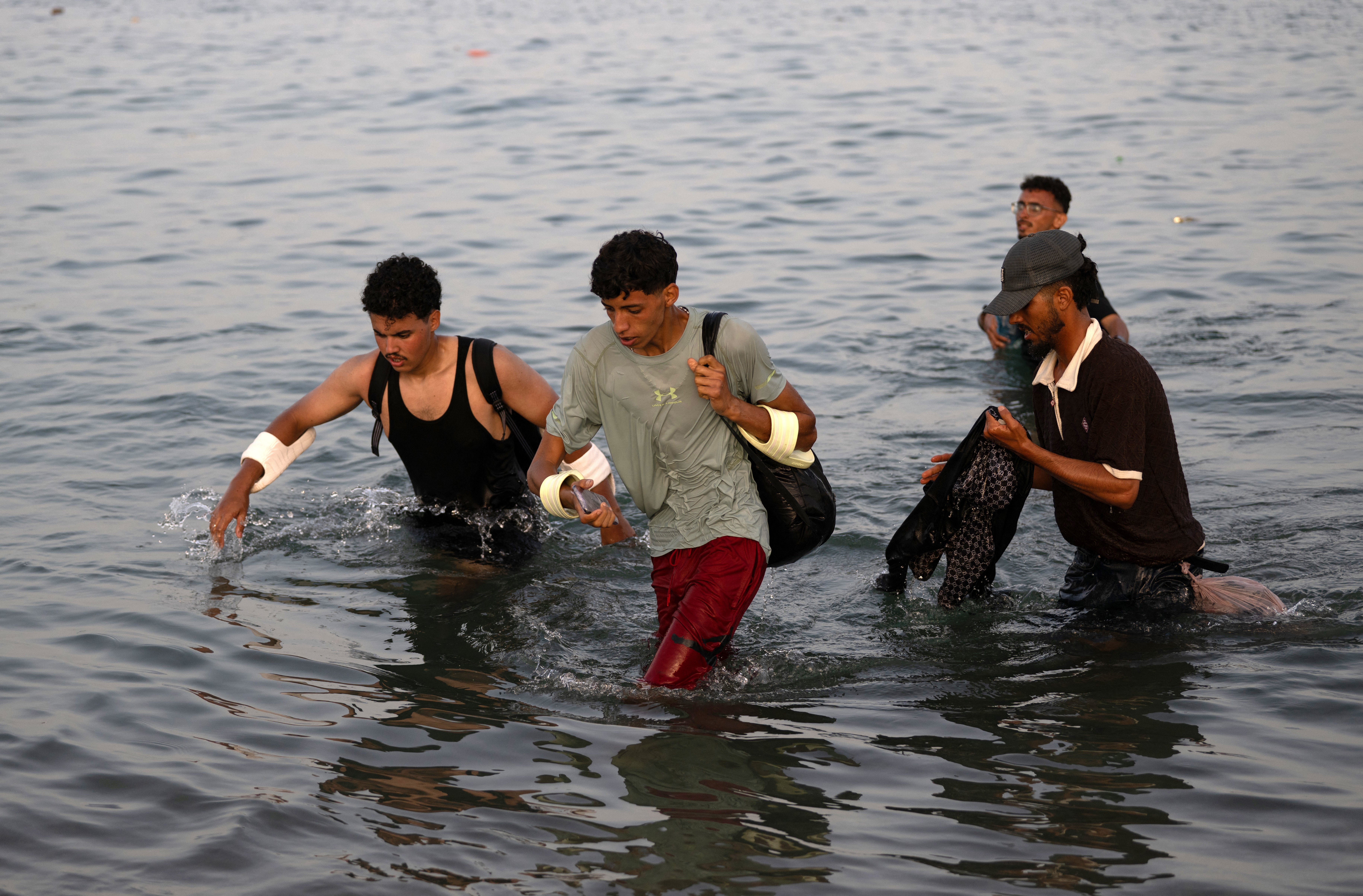 Migrants wade through the water near the border with Morocco