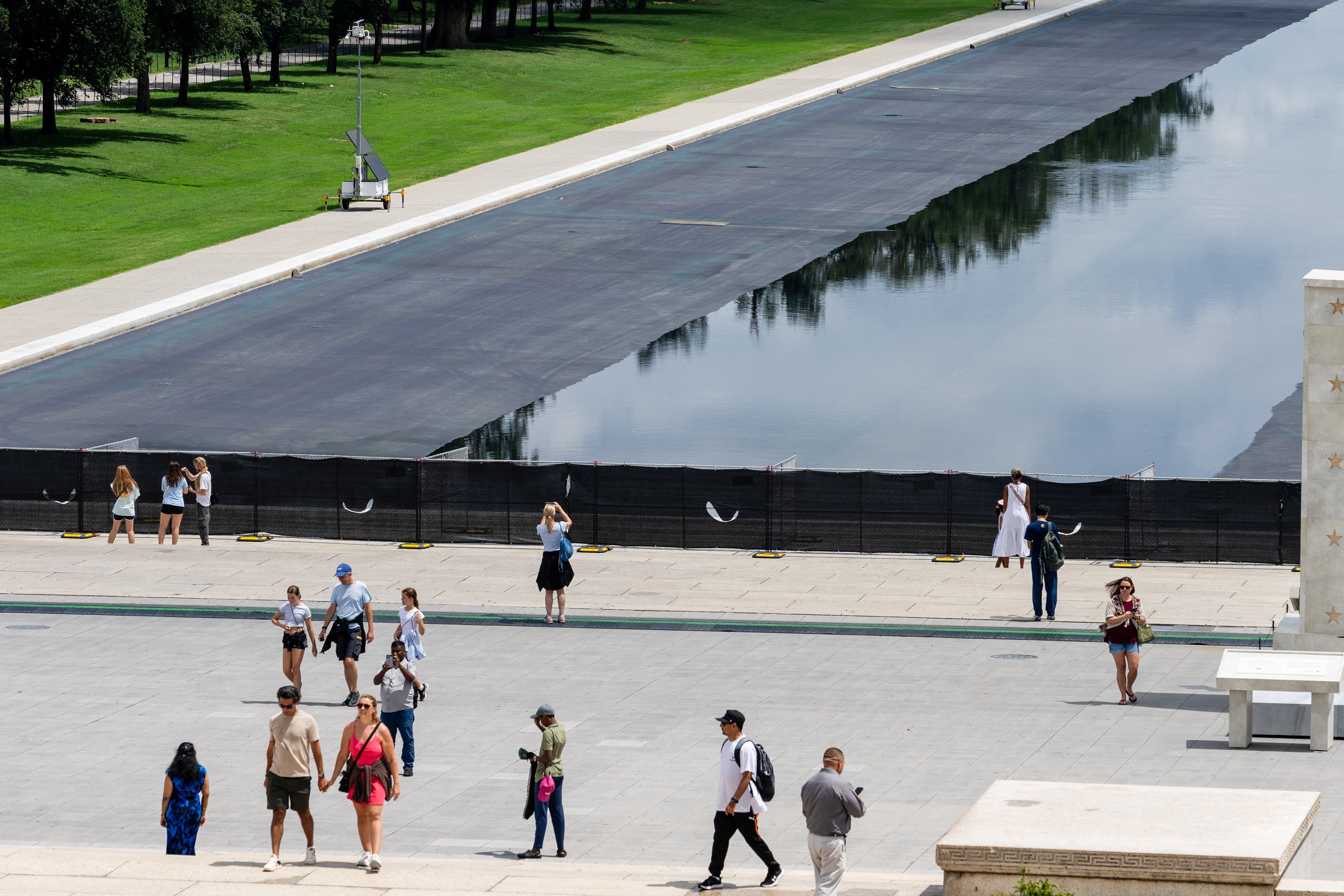 Members of nan nationalist tin spot nan Lincoln Memorial Reflecting Pool betwixt gaps successful nan chain-link obstruction covered successful fabric
