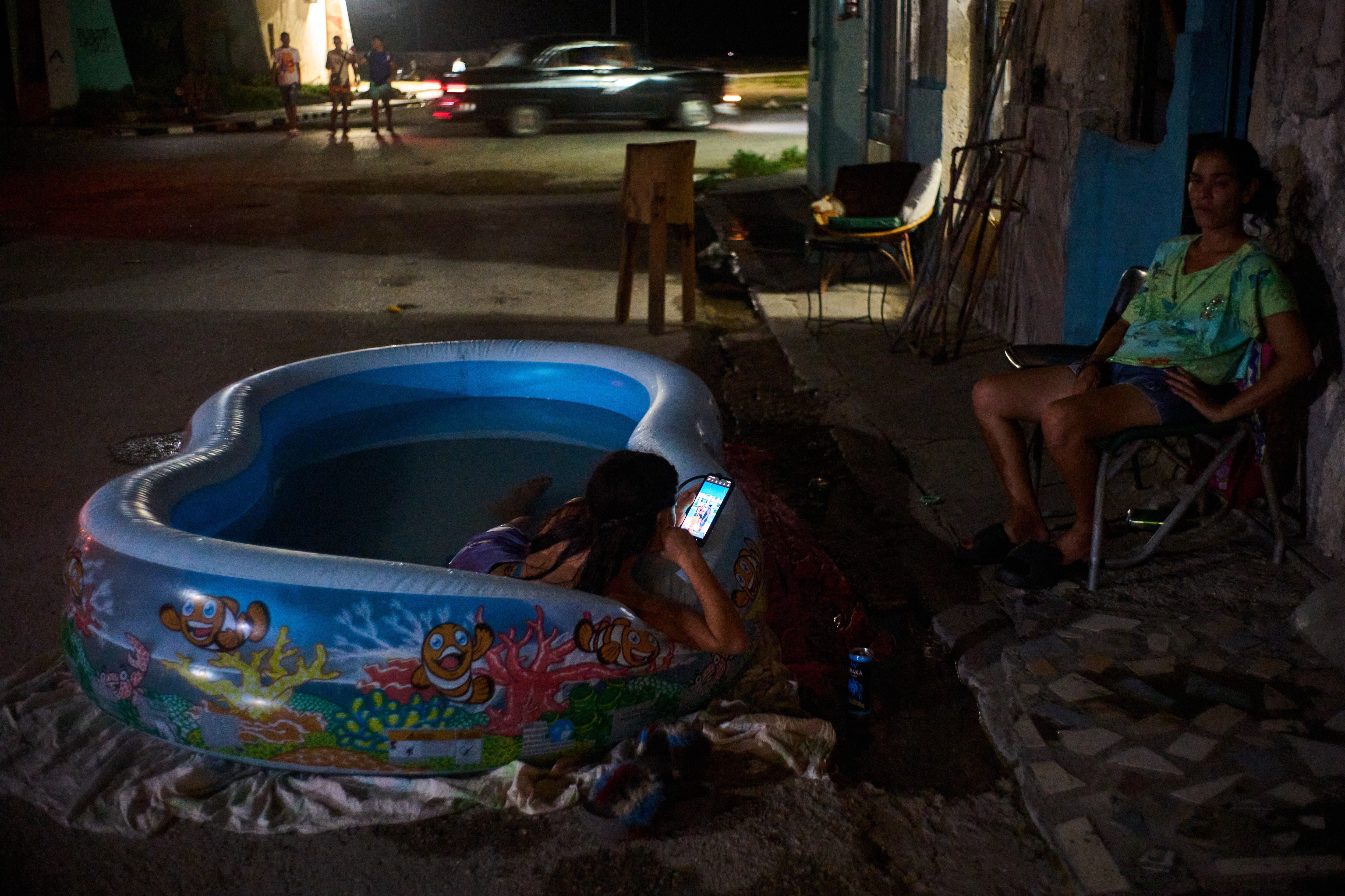 A girl cools off in a plastic pool in the street in Havana