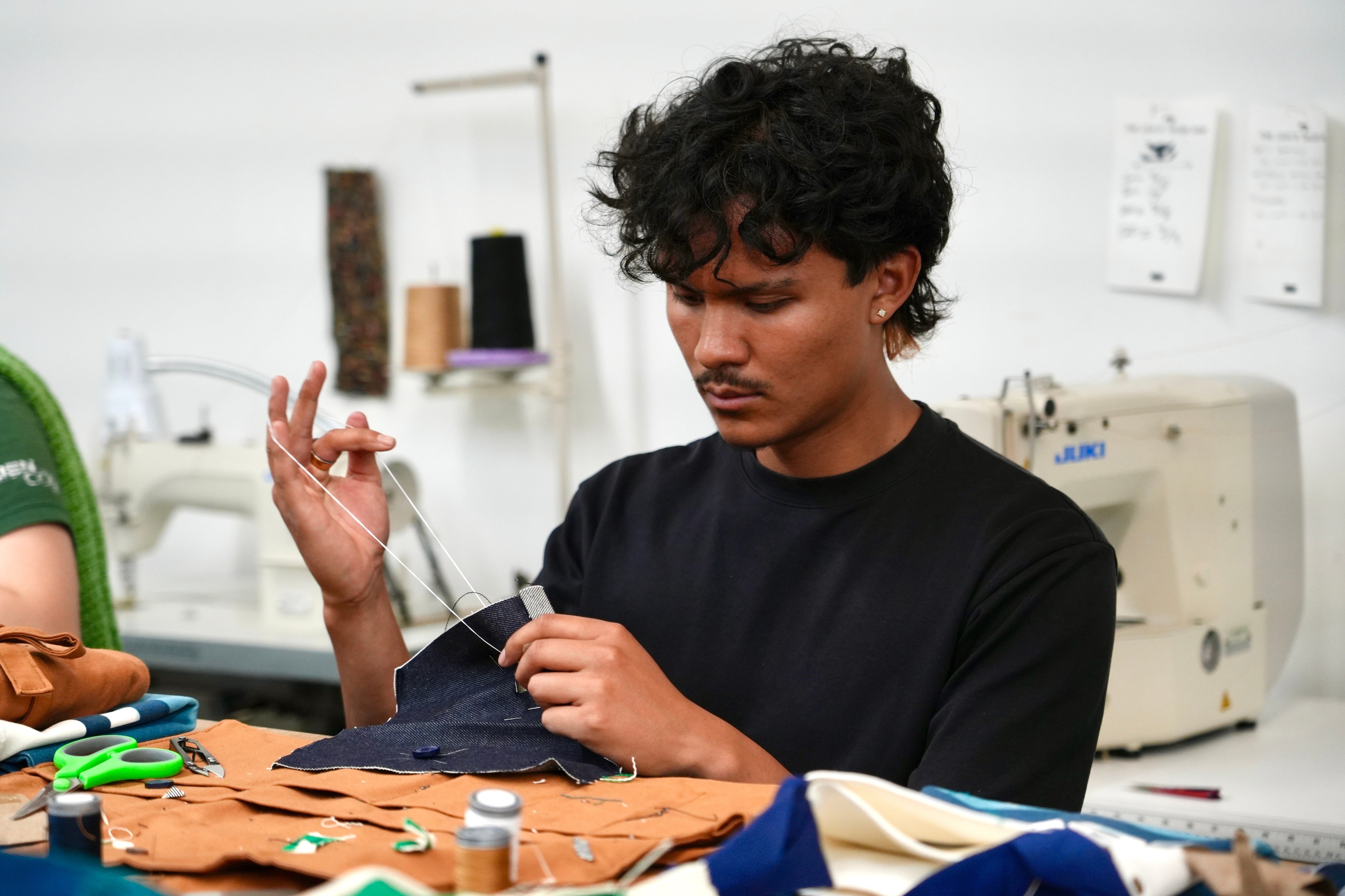 Jesse Sanchez practices sewing during a clothing repair workshop at a Levi's retail store in downtown San Francisco in July 2026