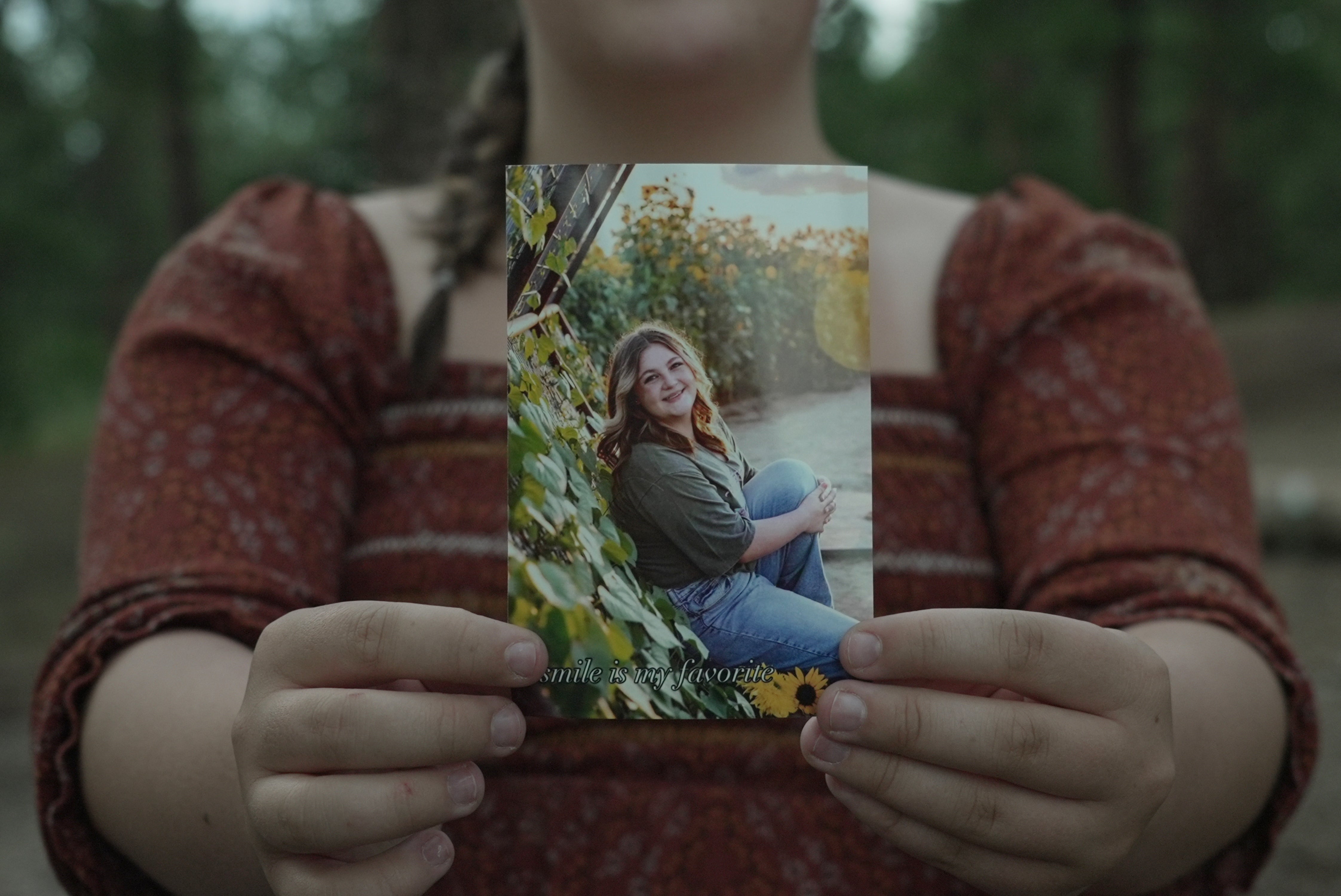 Charlotte Touzalin holds a photo of herself, provided by Bre Blake Photography, showing her before participating in a PMOS study, in Elizabeth, Colo., on Friday, July 10, 2026