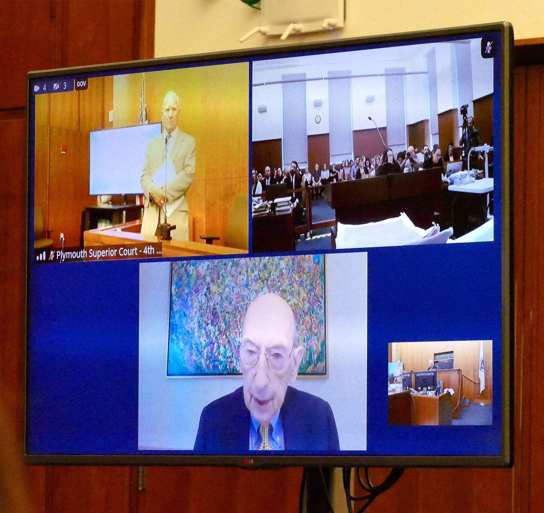 A screen shows defense attorney Kevin Reddington as he interviews witness Phillip Resnick, on remote feed, from Cleveland