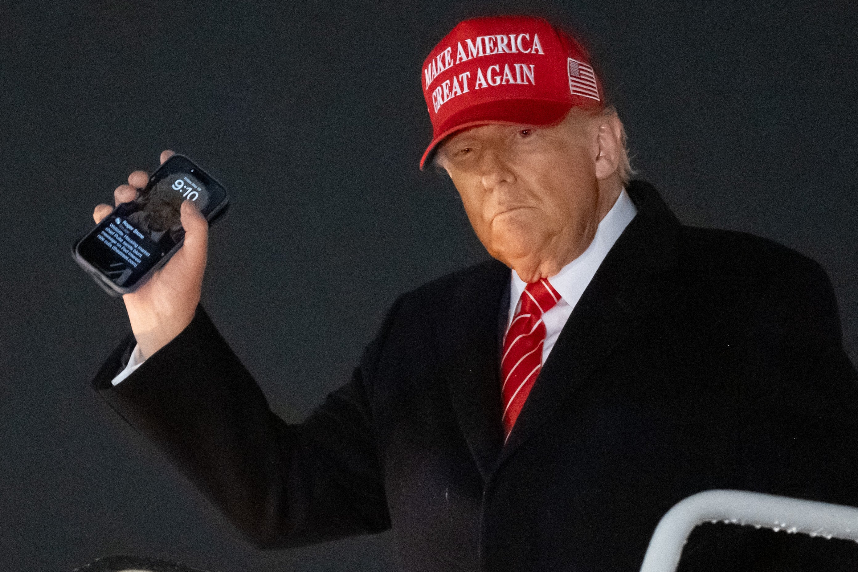 US President Donald Trump holds up a phone as he disembarks from Air Force One at Joint Base Andrews in Maryland, 30 May, 2025