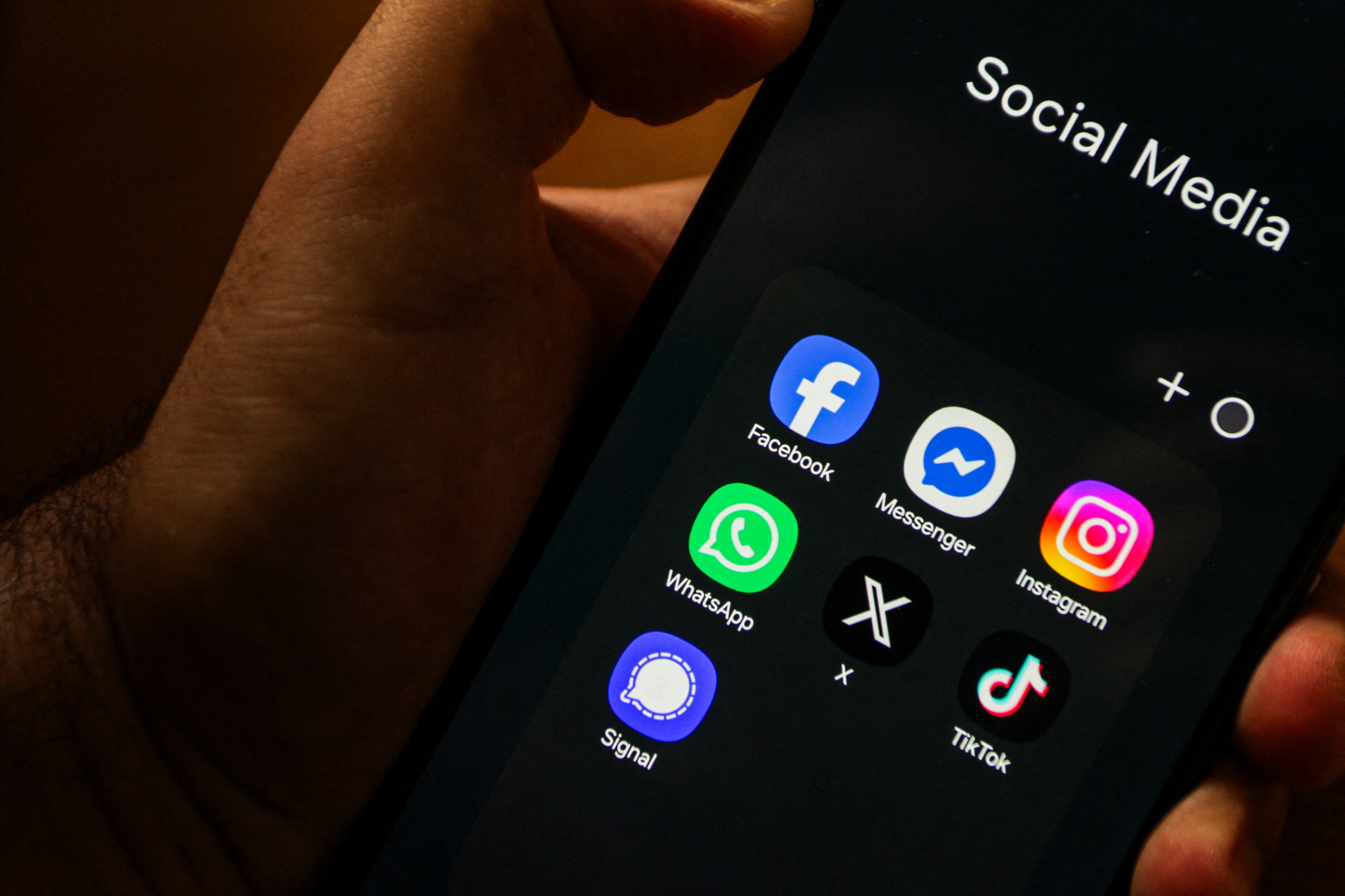 A close-up image of a hand holding a smartphone displaying social media applications