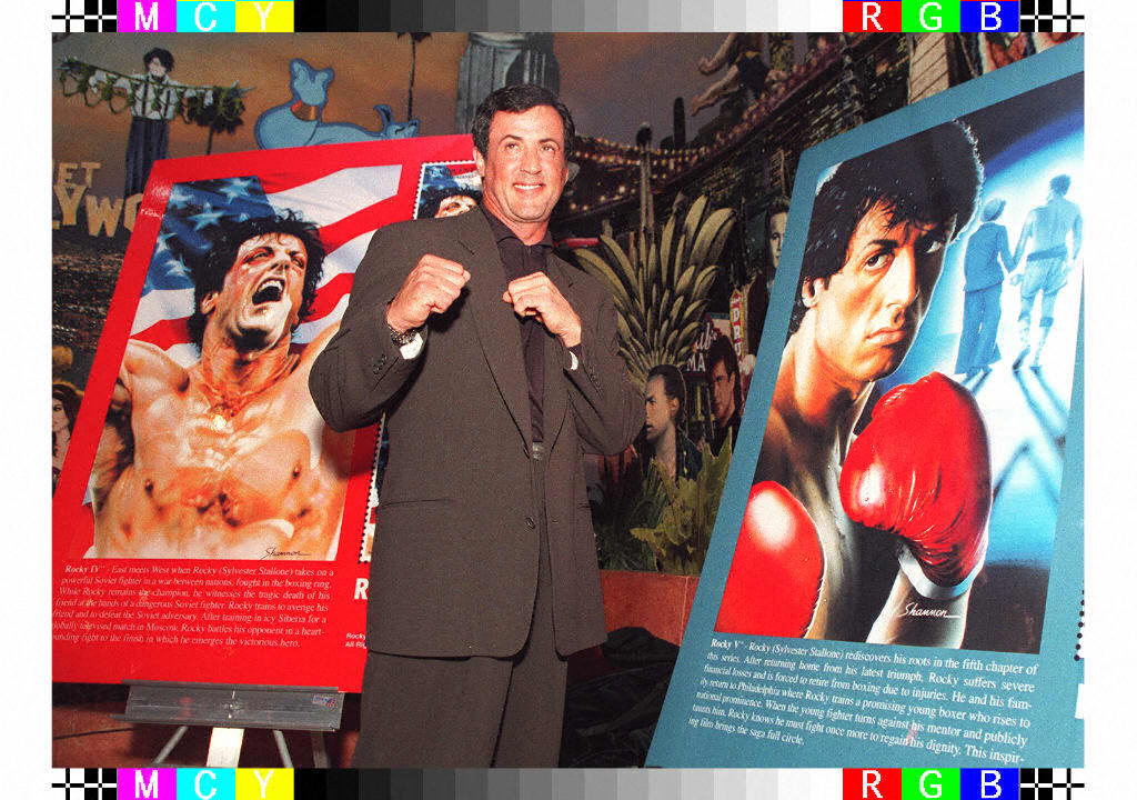 Sylvester Stallone poses with posters of the film ‘Rocky’