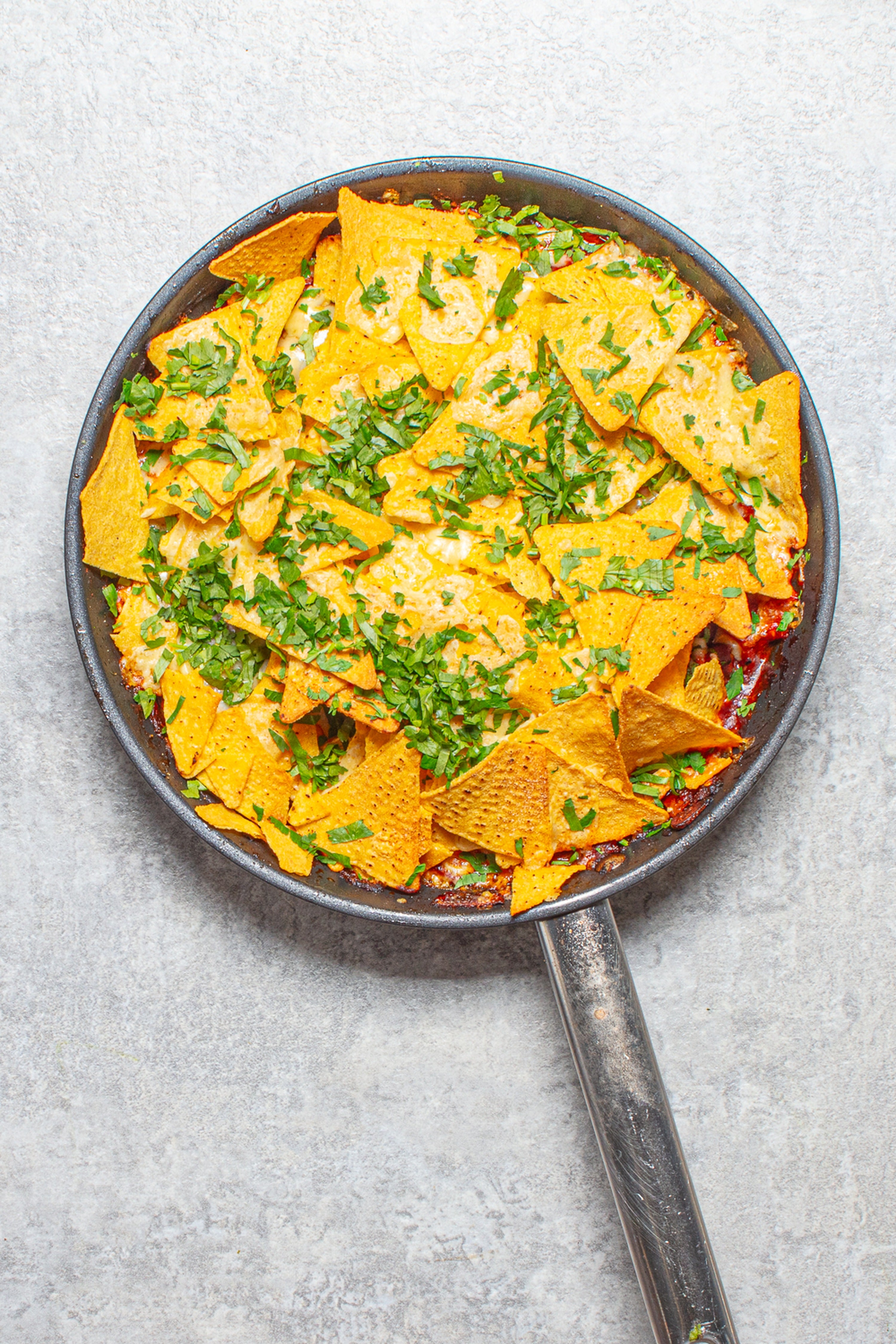 A bubbling chicken and bean bake topped with tortilla chips, melted cheese and coriander