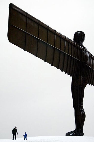 A father and son play in the snow beneath the Angel of the North near Gateshead