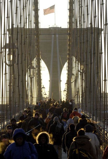 Pedestrians cross the Brooklyn Bridge into Manhattan at dawn