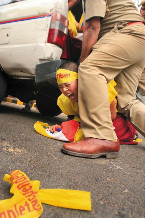 Indian police detain a Tibetan protesting in support of monks inside Tibet