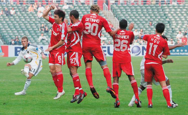 Beckham attempts to curl a free-kick beyond the defensive wall in a friendly against Hong Kong Union