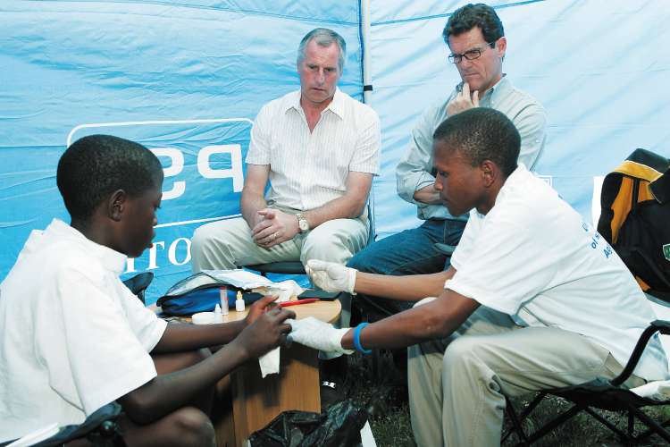 Fabio Capello (right) and RayClemence watch an HIV test in Maseru yesterday