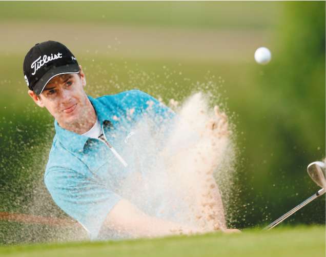 Tournament leader Scott Strange hits out of the bunker on the 17th hole during the third round at Celtic Manor