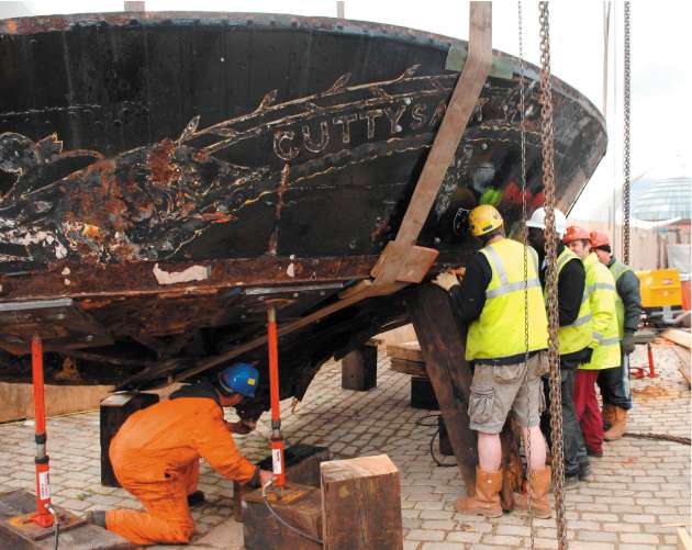 Workmen continue to restore the Cutty Sark after fire nearly destroyed the ship last year