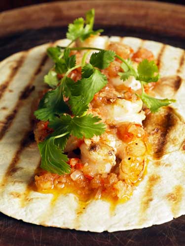 Warm the tortillas, lay on the prawns and top with the salsa and sprigs of coriander