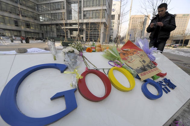 Bouquets of flowers lies upon the company logo as a man takes a photograph outside the Google China headquarters in Beijing last week