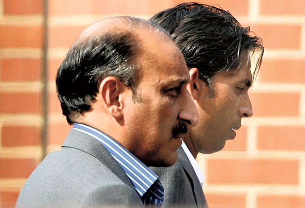 The Pakistan bowler Mohammad Asif, right, arrives with an unidentified man at a police station